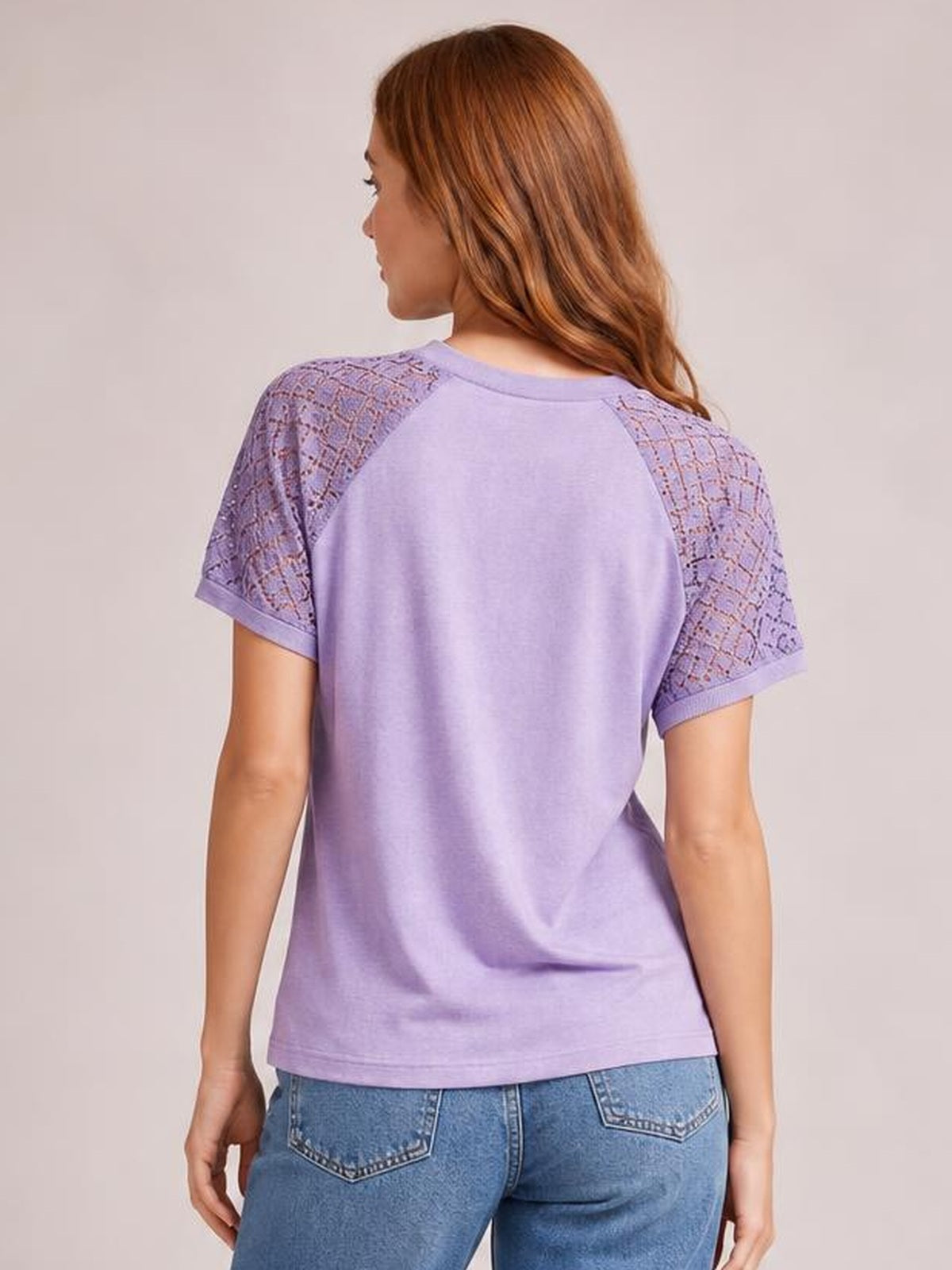 Model shown from behind wearing a lavender round neck short sleeve T-shirt with lace shoulder and sleeve panels and a relaxed, straight silhouette.