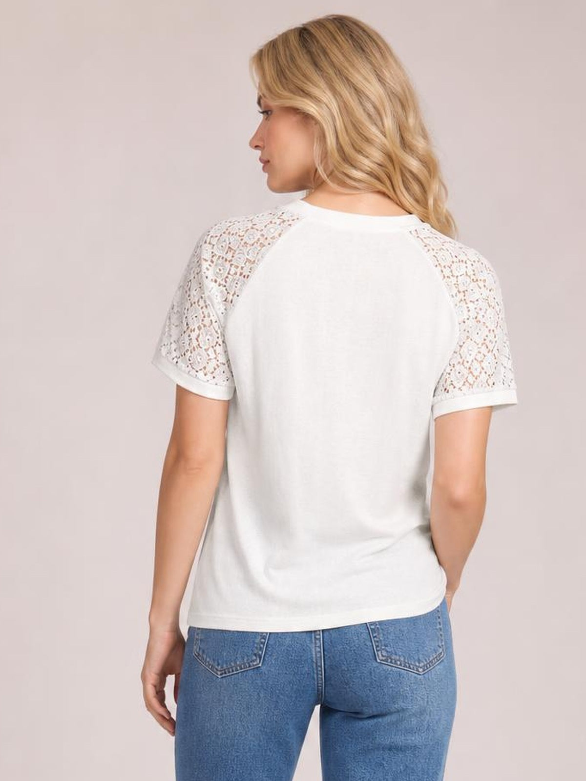 Model shown from the back wearing a white round neck short sleeve T-shirt with lace shoulder panels, rolled cuffs, and a relaxed straight silhouette.