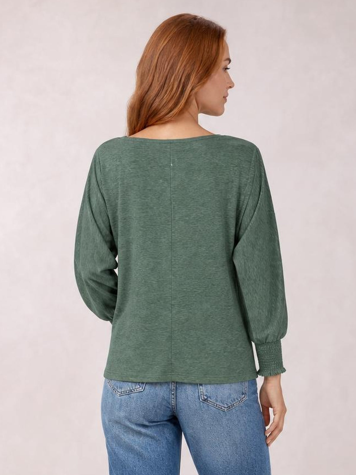 A model seen from behind wears a sage green round-neck T-shirt with voluminous smocked lantern sleeves, gathered cuffs, and a relaxed straight silhouette.