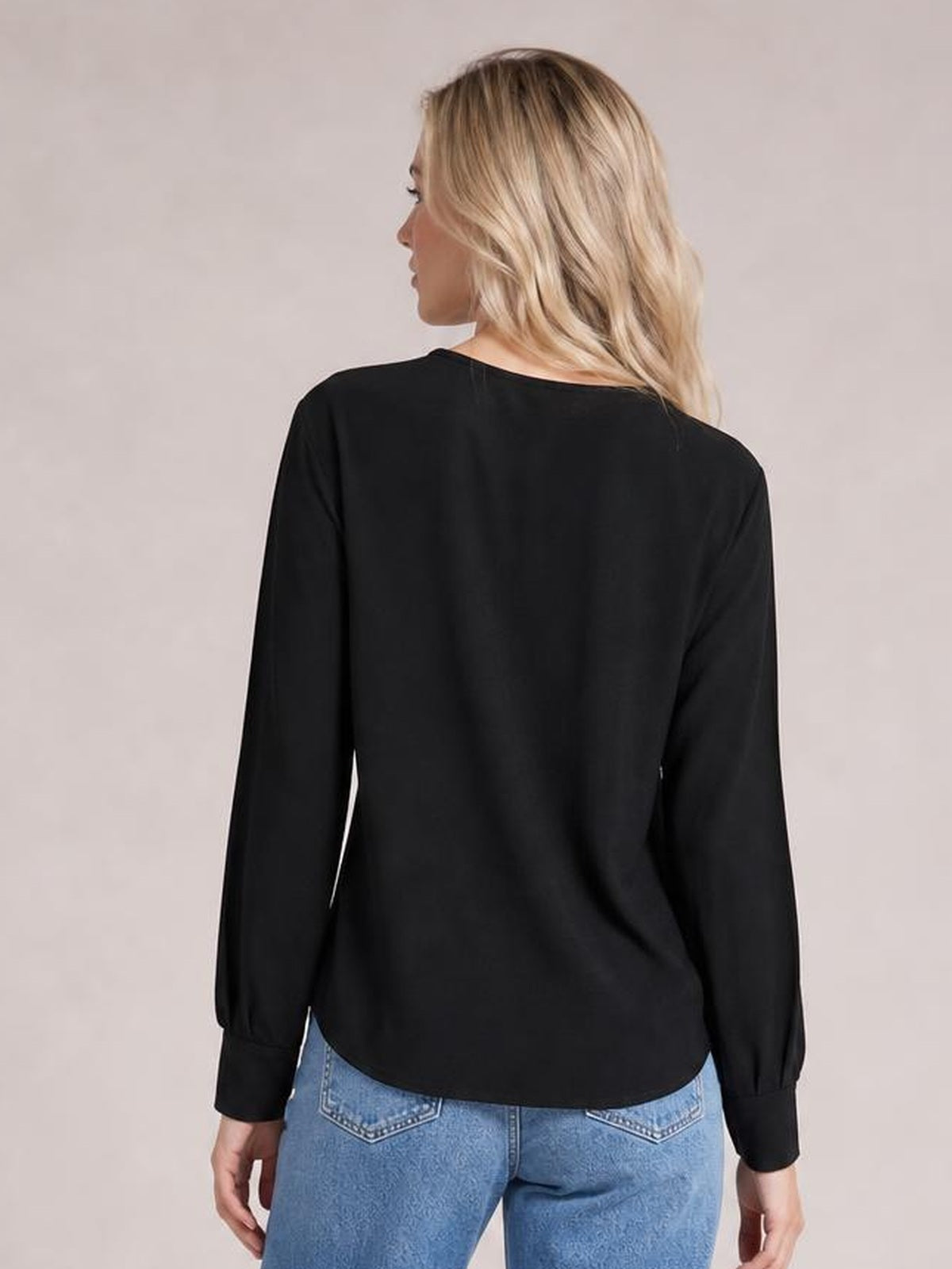 A model shown from behind wears a black round-neck T-shirt with long lantern sleeves, gathered cuffs, and a relaxed, slightly curved hem.