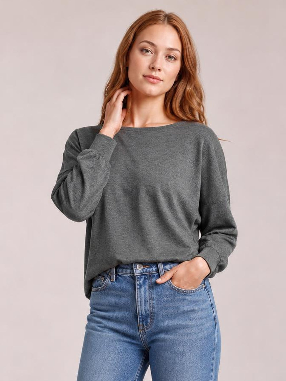 Model wears a charcoal gray round-neck T-shirt with relaxed lantern sleeves, ribbed cuffs, and a loose silhouette tucked into high-waisted jeans.