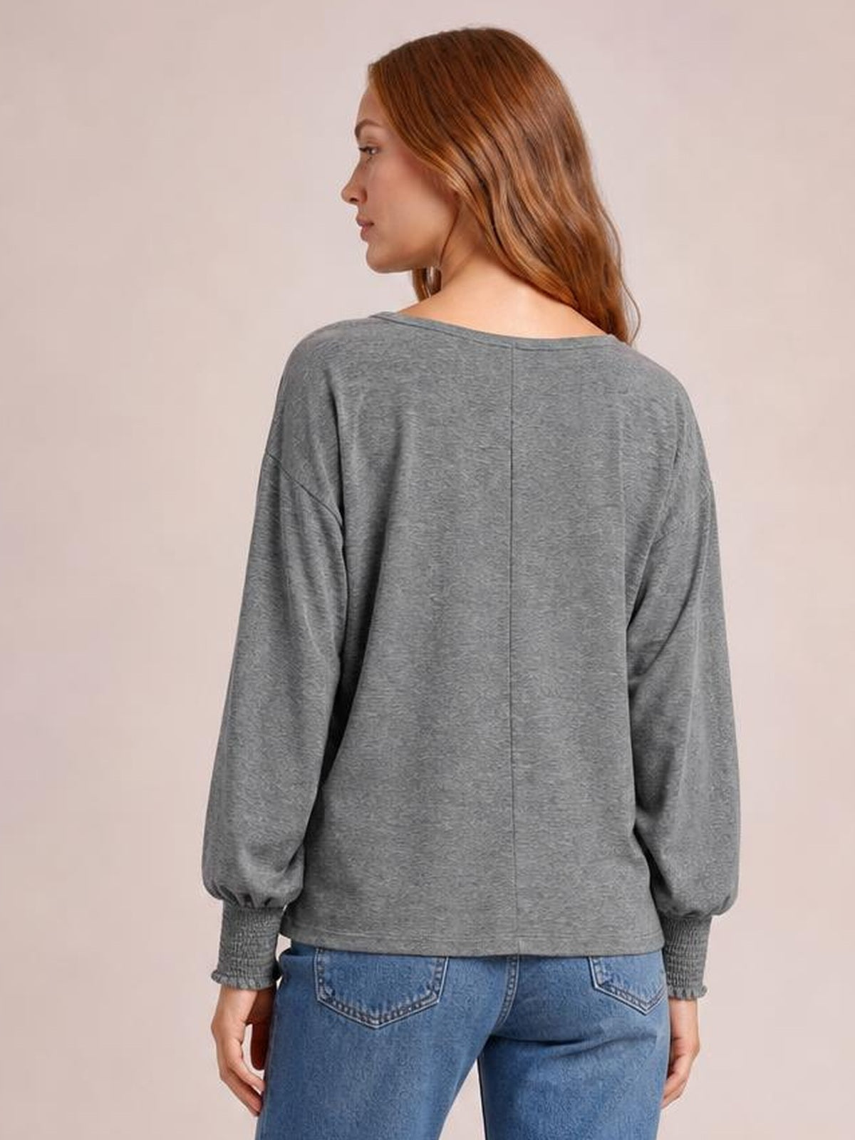 A model shows the back of a gray round neck t-shirt with a relaxed silhouette, voluminous lantern sleeves, and smocked cuffs.