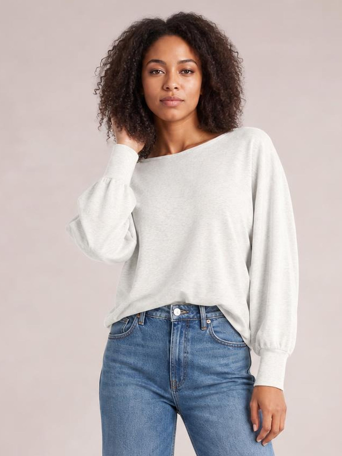 A model poses in a light gray round-neck t-shirt with voluminous smocked lantern sleeves, gathered cuffs, and a relaxed straight silhouette.