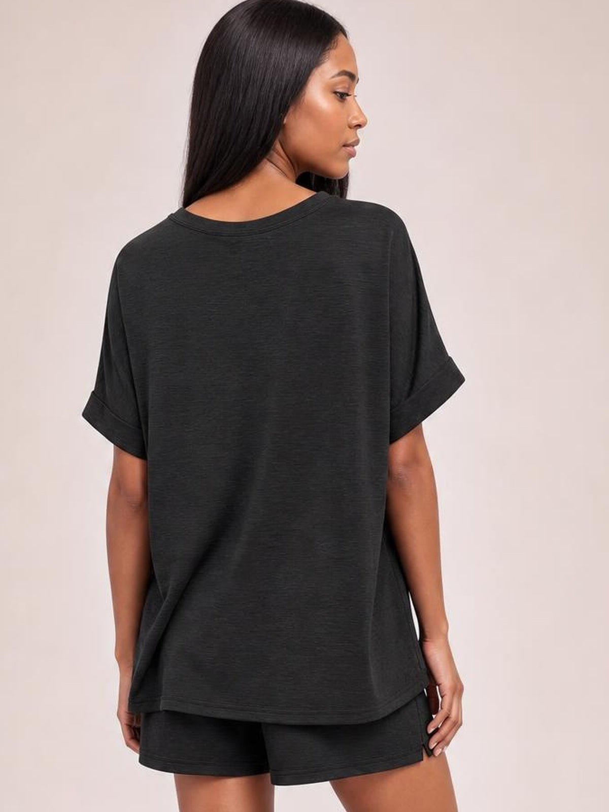 Model shown from the back in a black round neck T-shirt and drawstring shorts set, featuring a relaxed oversized silhouette, rolled sleeves, and side pockets.