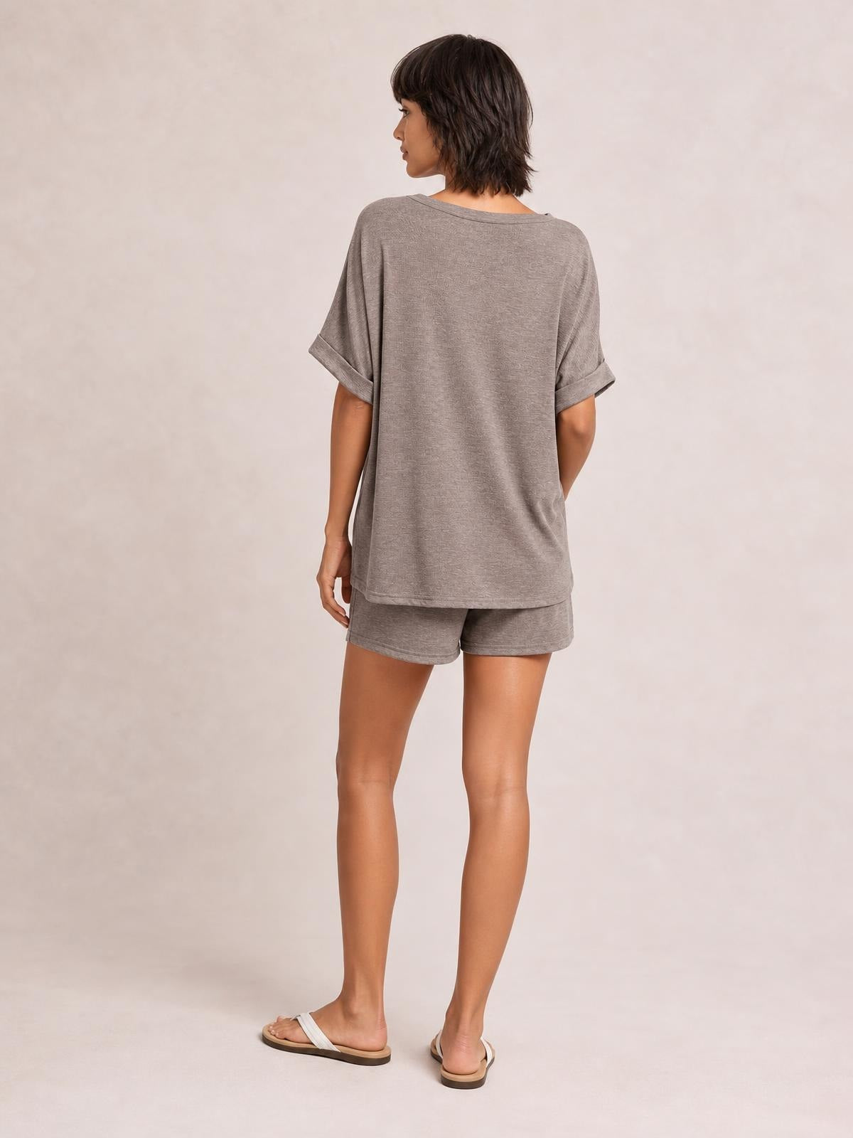 Model shown from behind wearing a loose gray round neck T-shirt and matching drawstring shorts set with cuffed sleeves and relaxed silhouettes.