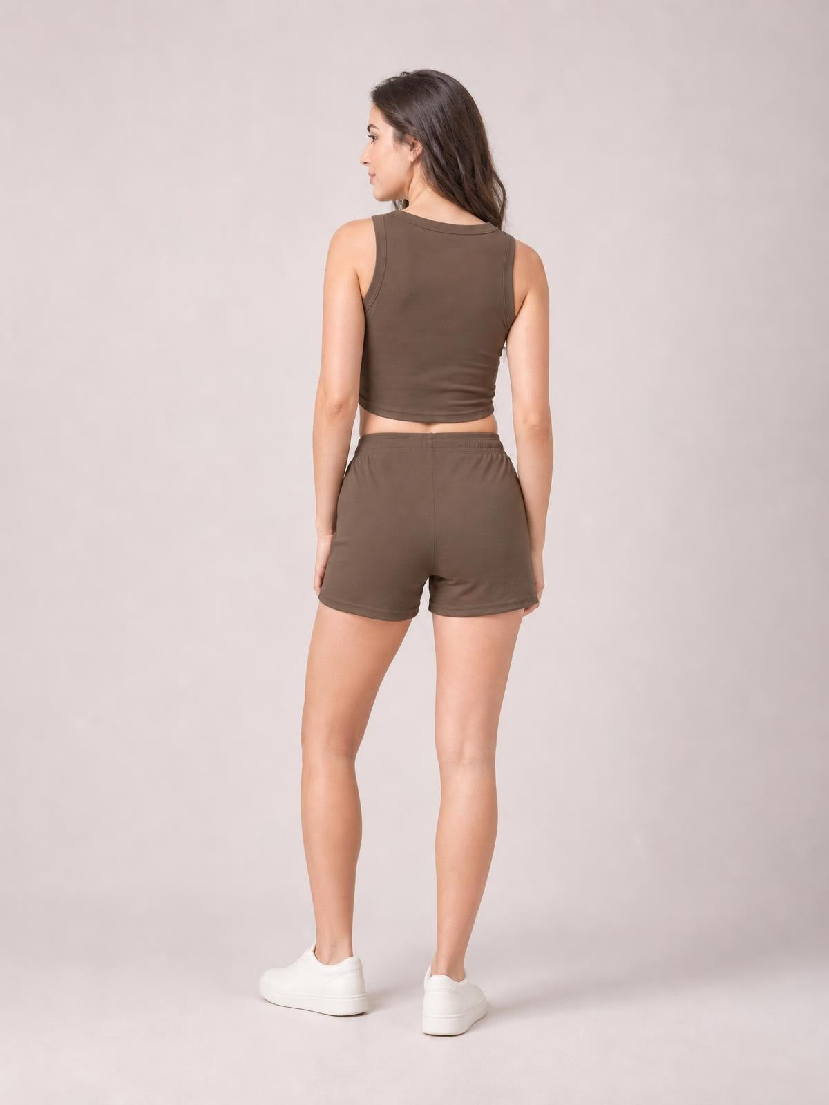 A model stands in a back-facing pose wearing a brown round-neck tank with a fitted cropped silhouette and matching relaxed drawstring shorts.