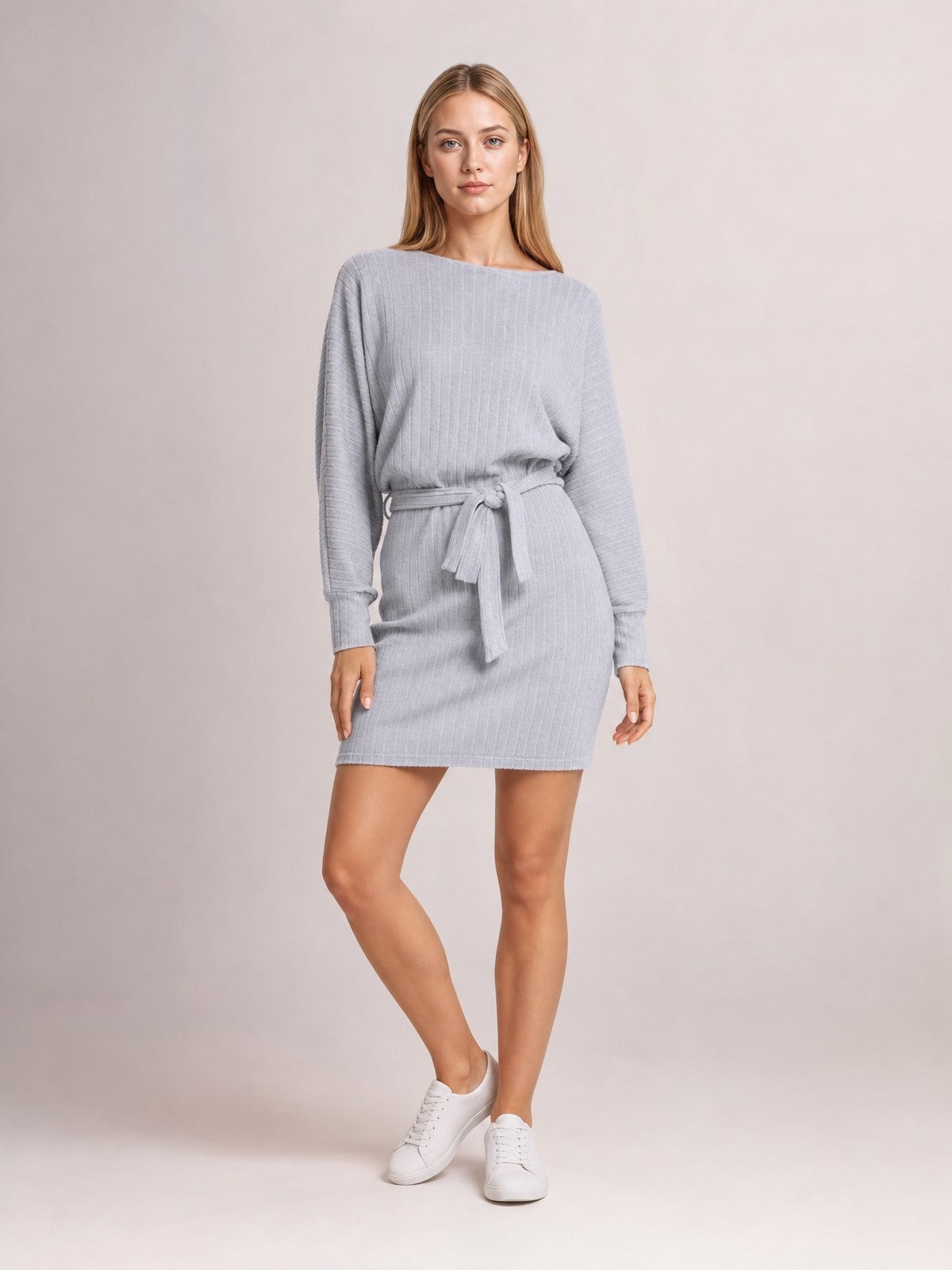A model poses in a gray textured mini dress with a round neck, long balloon sleeves, fitted cuffs, and a self-tie waist defining its relaxed silhouette.
