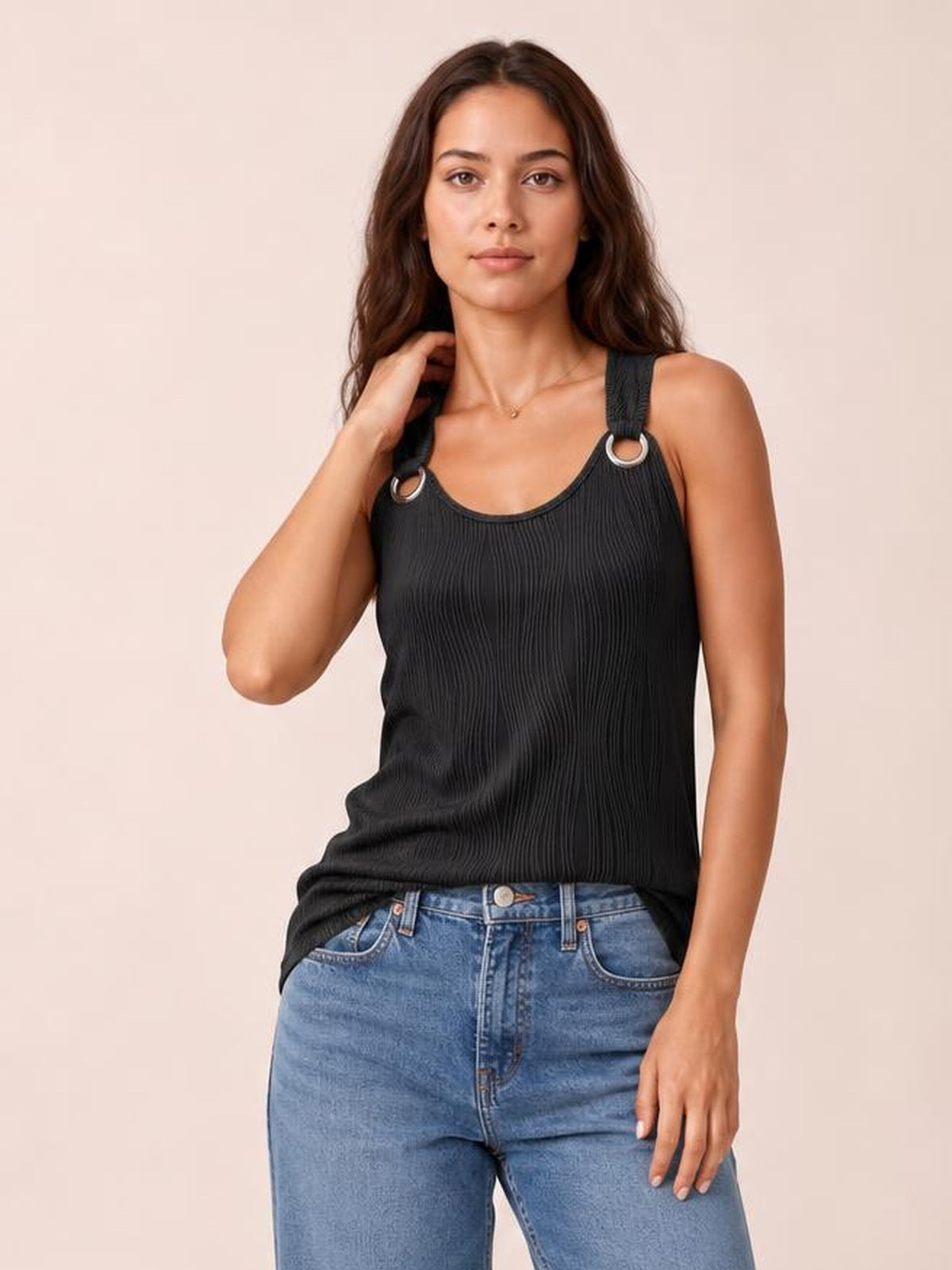 Model wears a black round-neck wide-strap tank with a relaxed silhouette, vertical ribbed texture, and silver ring strap details, posing with one hand near her hair.