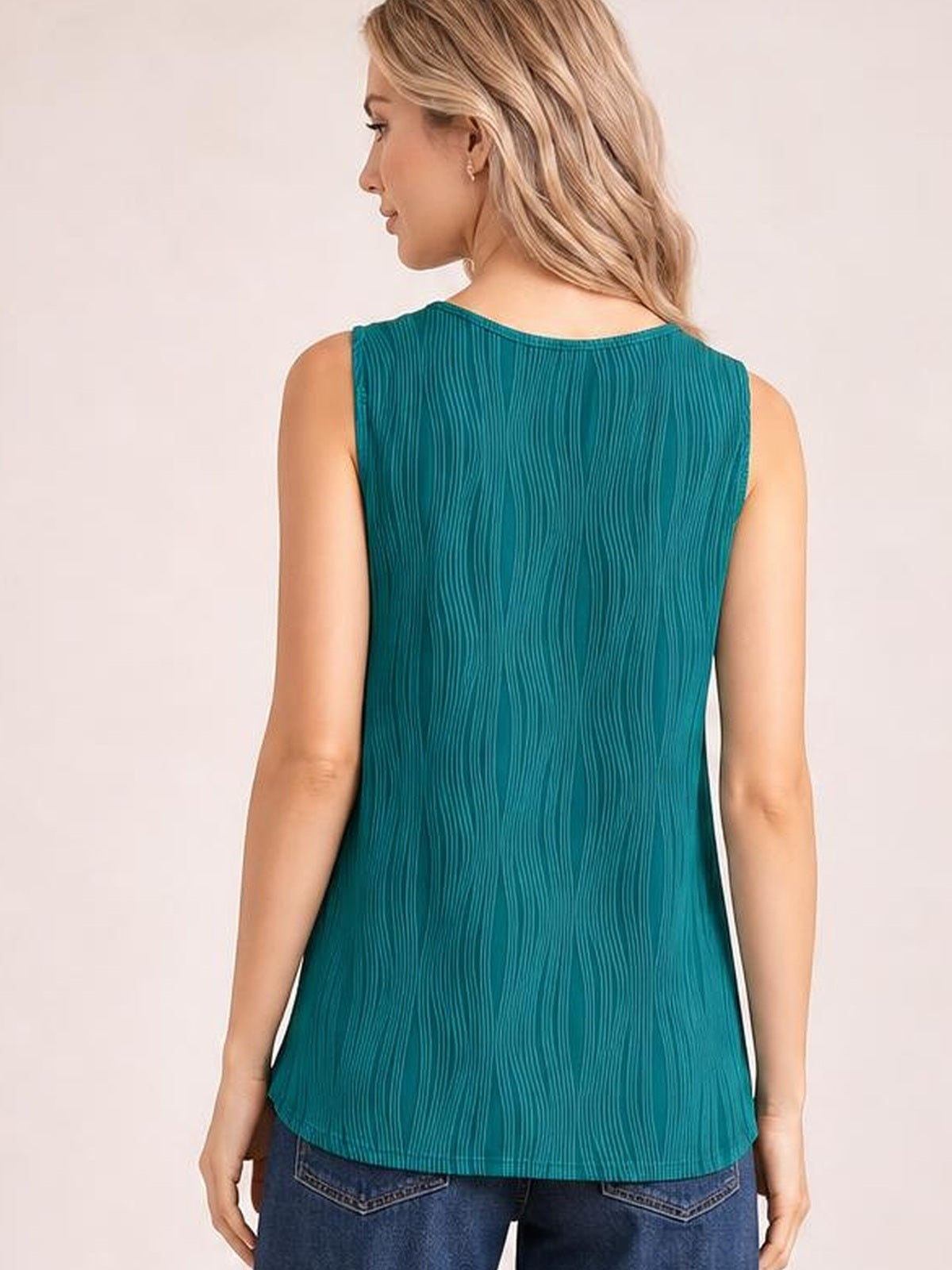 A model wears a teal round neck wide strap tank with a relaxed straight silhouette, curved hem, and subtle vertical texture, shown from the back.
