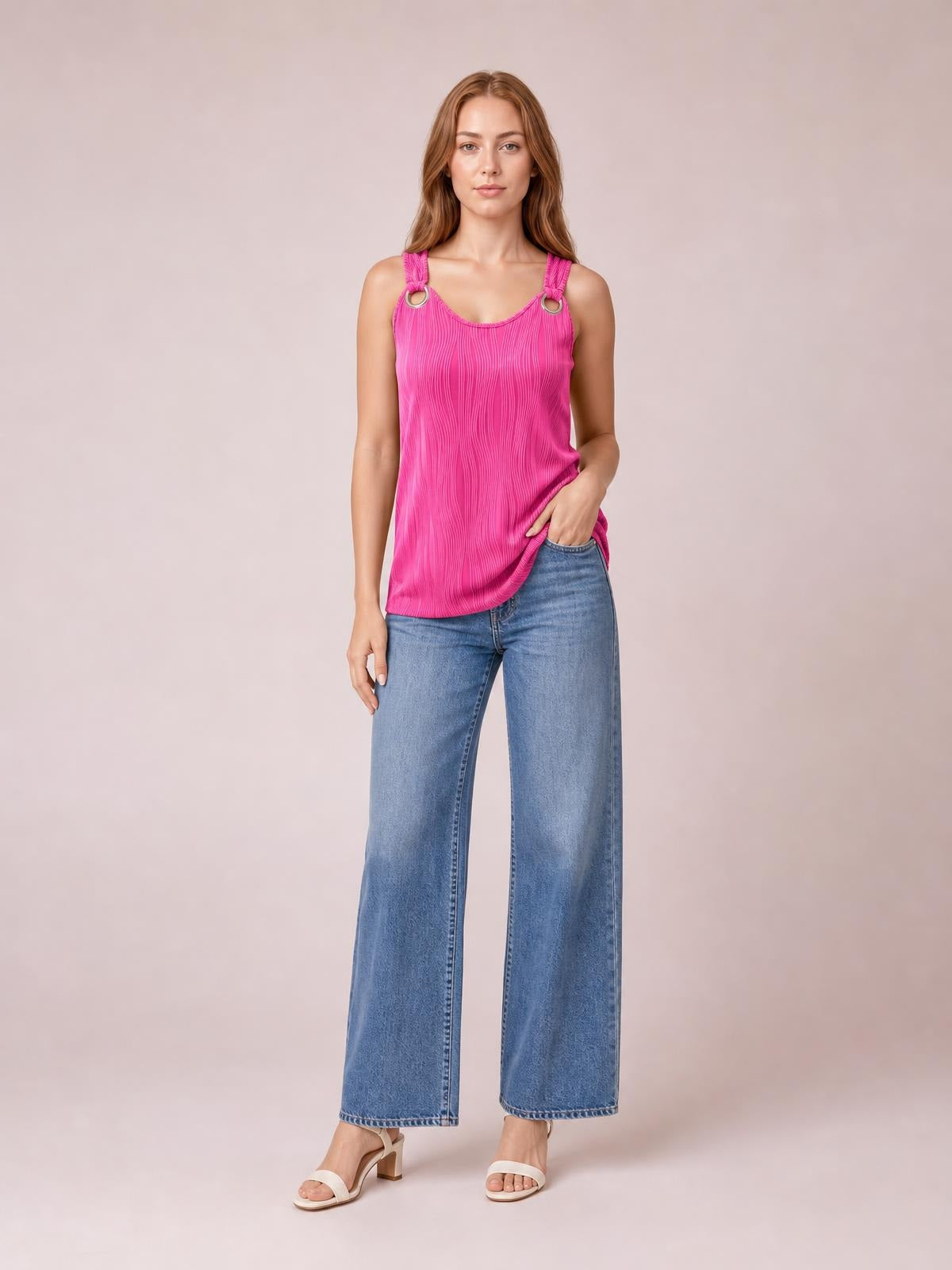 Model poses in a bright pink round neck wide strap tank with gathered shoulder straps, ring details, and a relaxed straight silhouette over wide-leg jeans.
