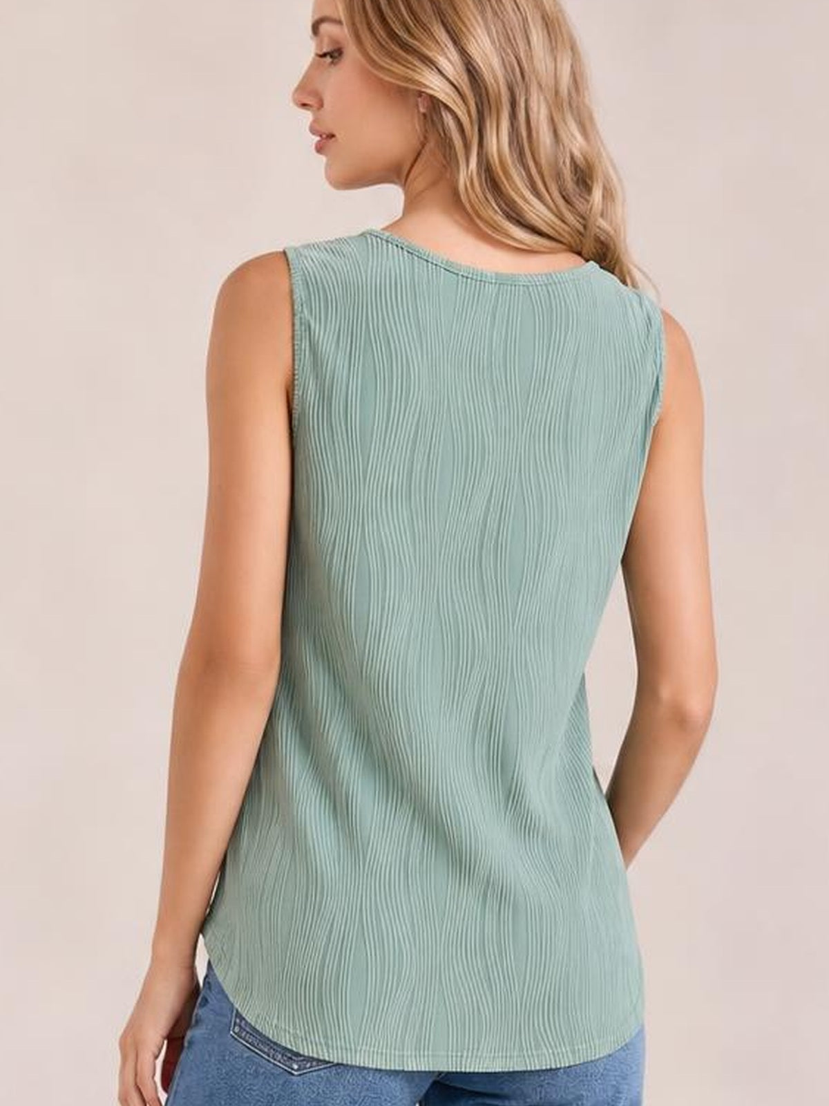 Model shown from behind wearing a sage green round neck wide strap tank with vertical ribbed texture, relaxed silhouette, and curved hem over jeans.