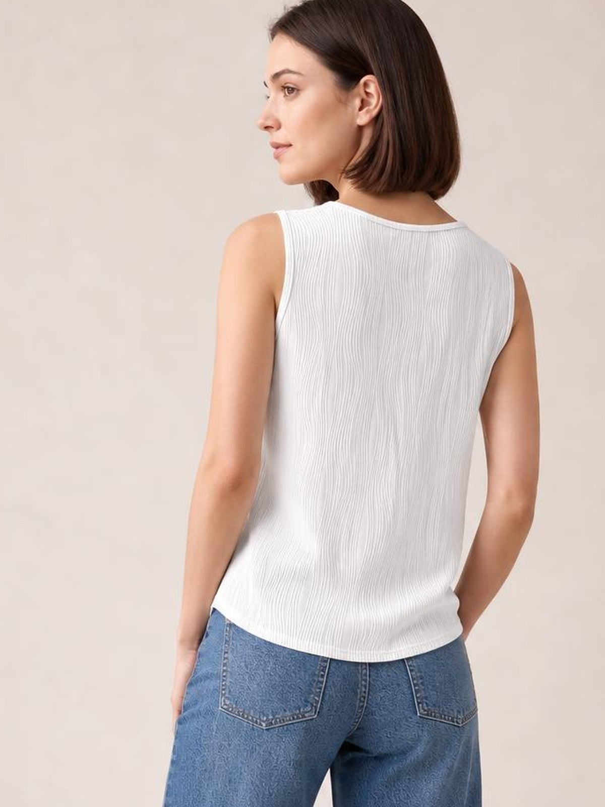 A model turns to show a white round-neck wide-strap tank with vertical texture, clean binding, and a relaxed straight silhouette.