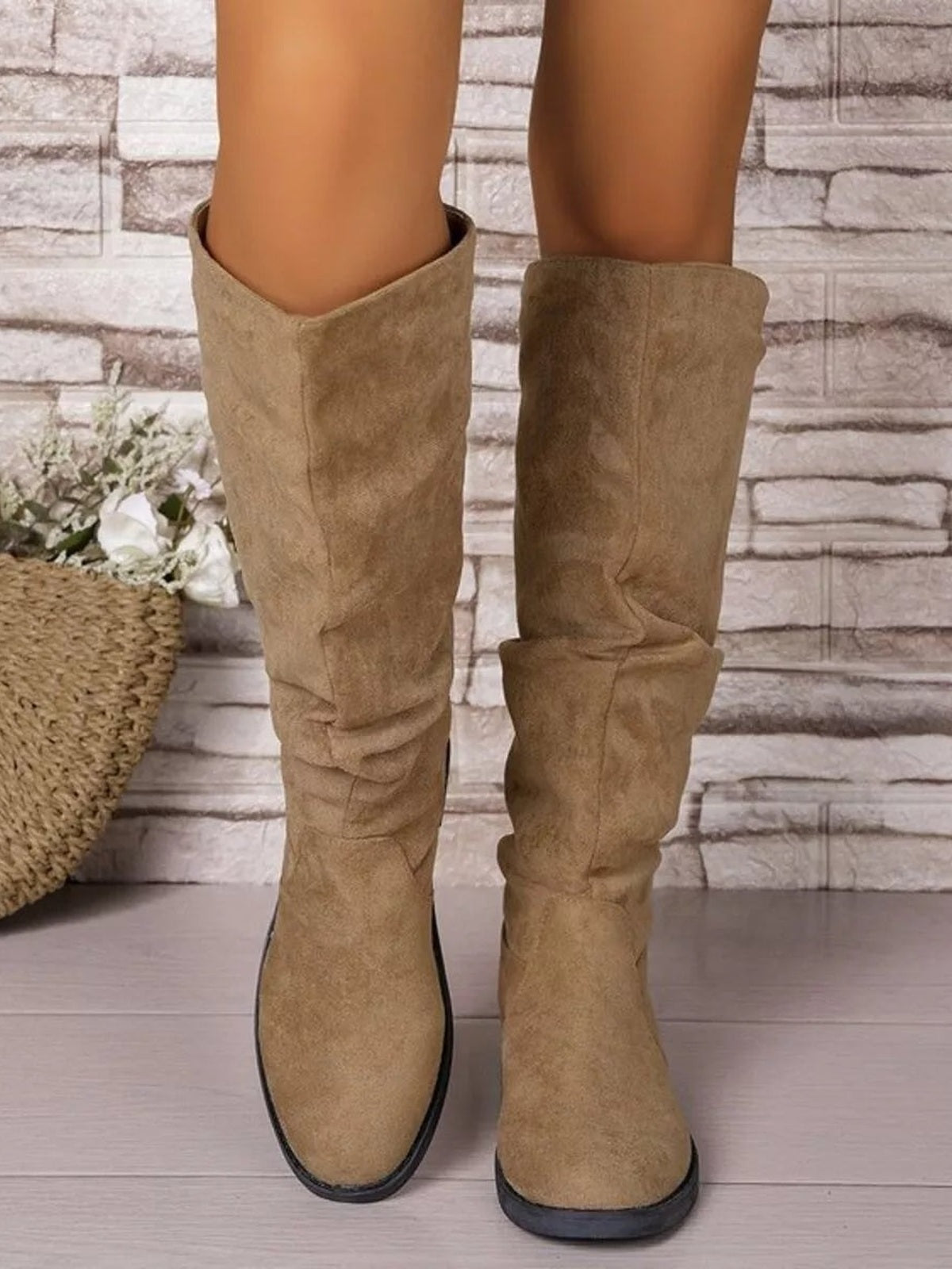 A model wears tan PU leather knee-high boots with softly ruched shafts, round toes, and sturdy rubber soles in a straight standing pose.
