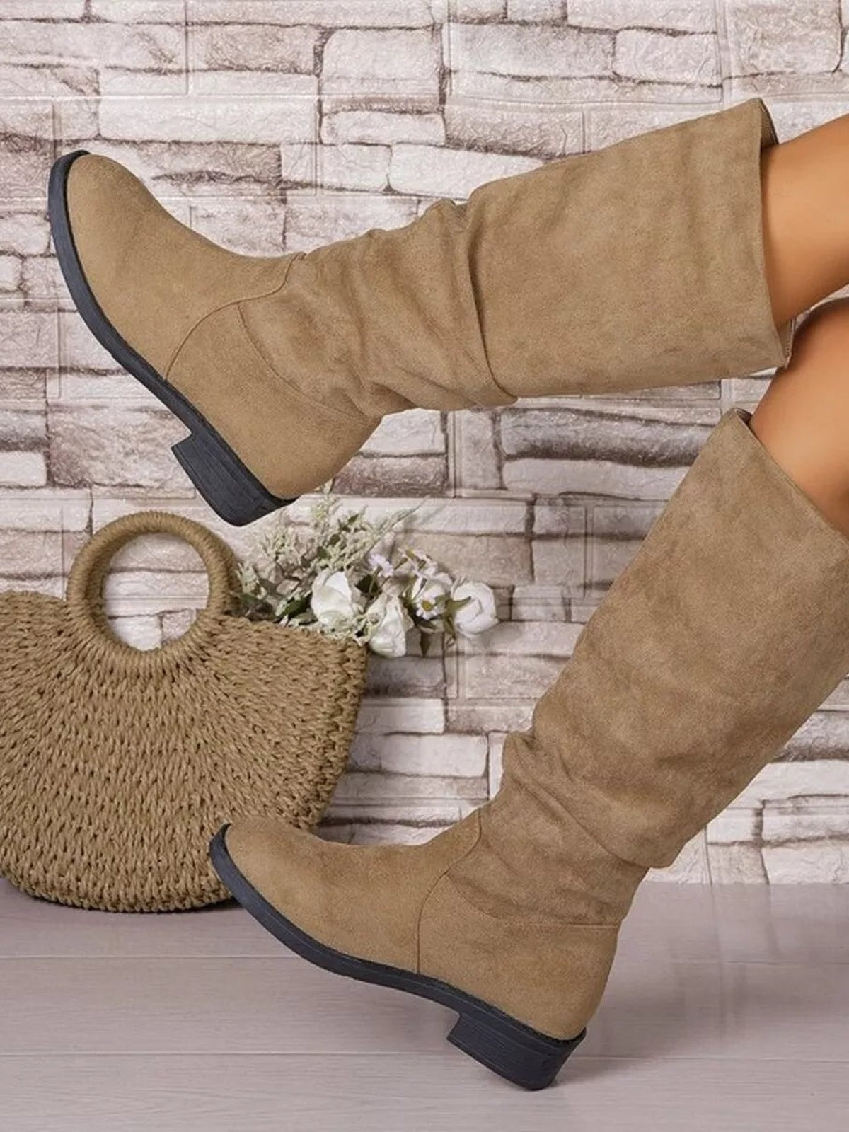 A model poses with crossed legs in tan PU leather boots featuring round toes, tall fitted shafts, visible panel seams, and sturdy mid-height block heels.