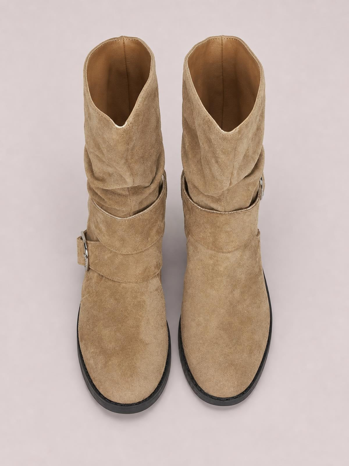 Tan round-toe block heel boots feature wraparound ankle straps with buckles, a soft textured finish, and contrasting black rubber soles.