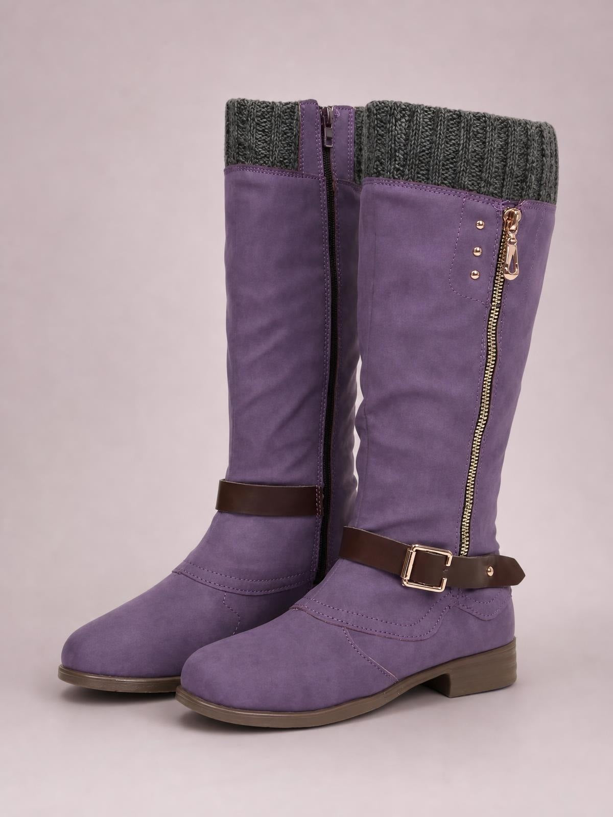 Pair of purple suede round-toe boots with mid-height block heels, ribbed knit cuffs, side zippers, buckle straps, and rubber soles.