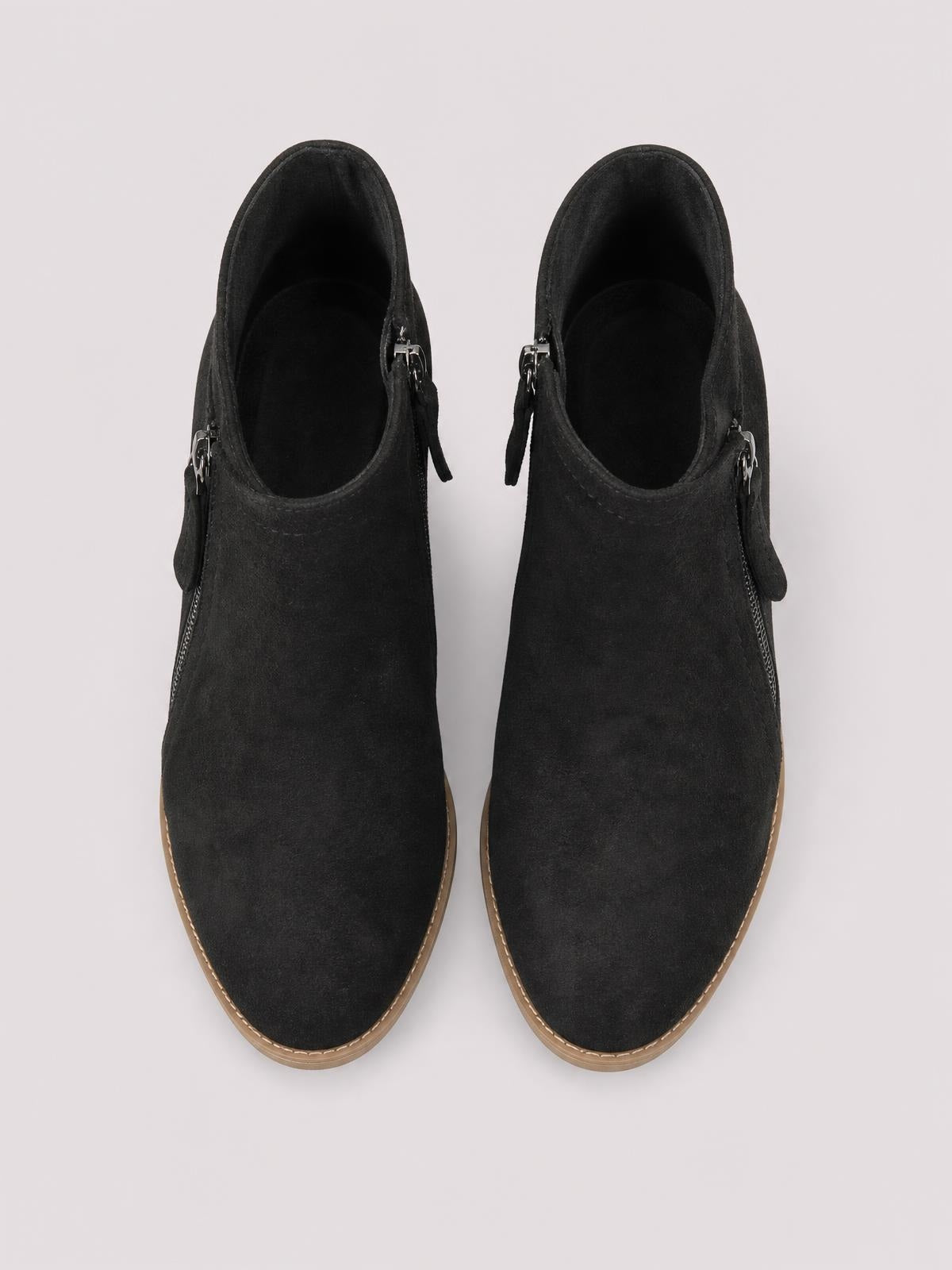Pair of black PU leather ankle boots with round toes, side zippers, low block heels, and contrasting rubber soles shown from above.
