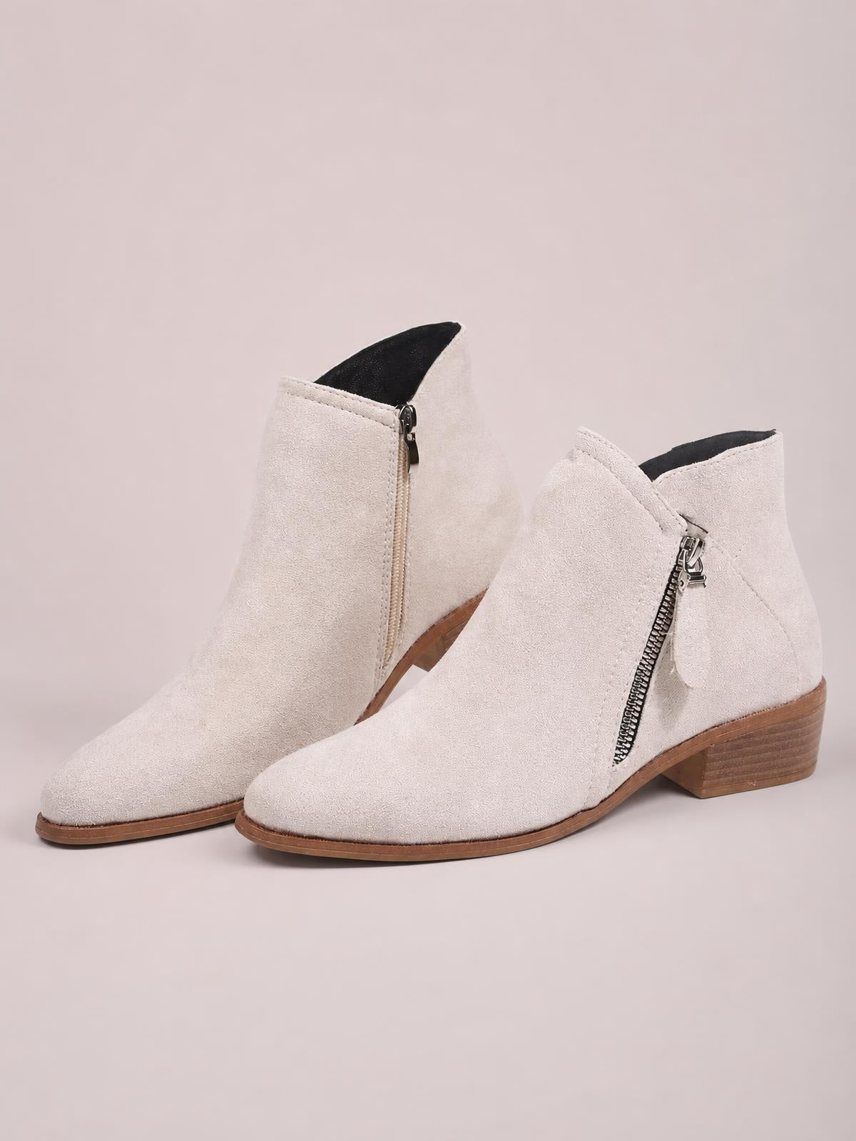 Light beige PU leather ankle boots feature rounded toes, low stacked block heels, side zippers, and a clean pull-on silhouette.