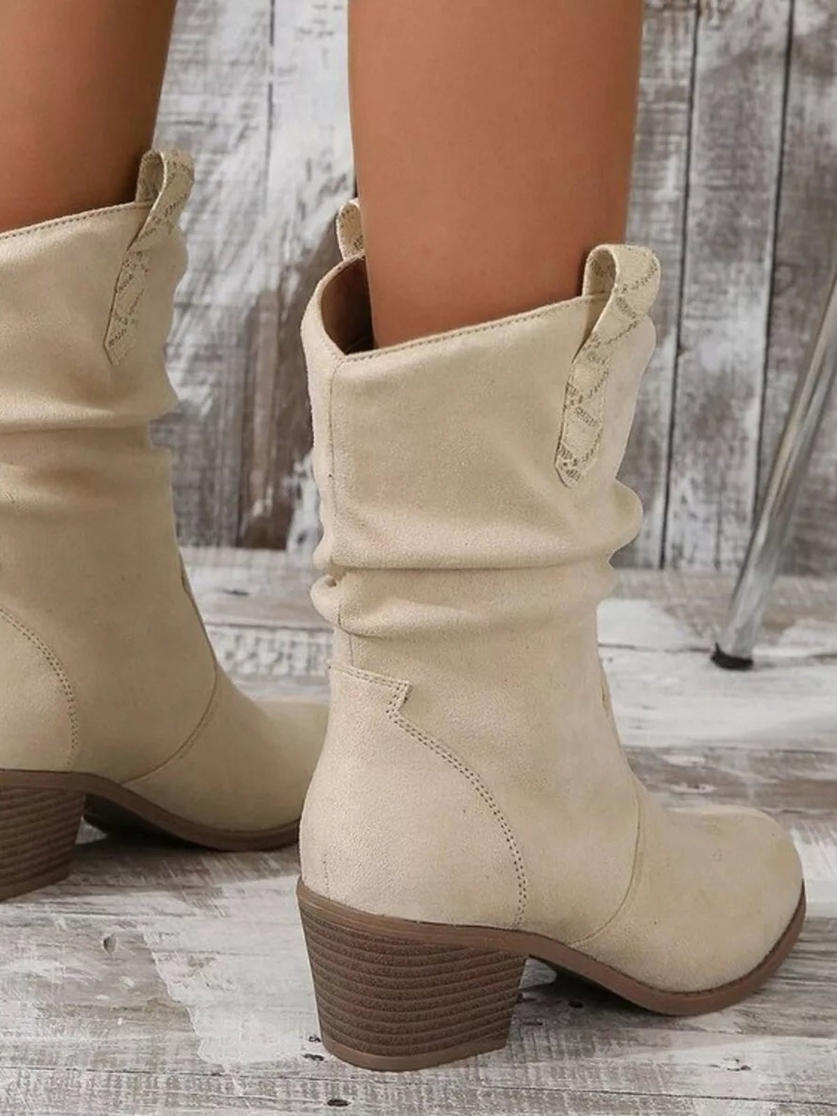 Beige PU leather boots feature a slouchy shaft, round toes, stitched panel construction, pull tabs, and low textured block heels.