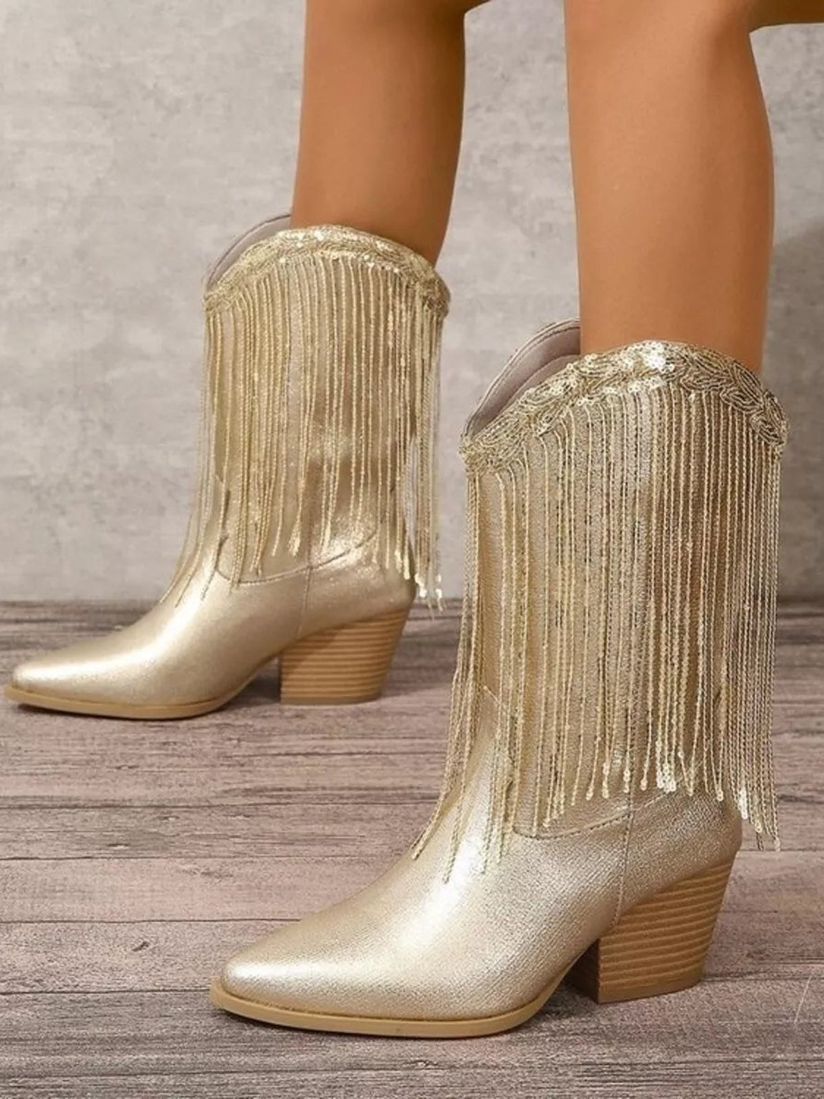 Metallic gold ankle boots with round toes, low stacked block heels, and long fringe detailing draped over the shafts.