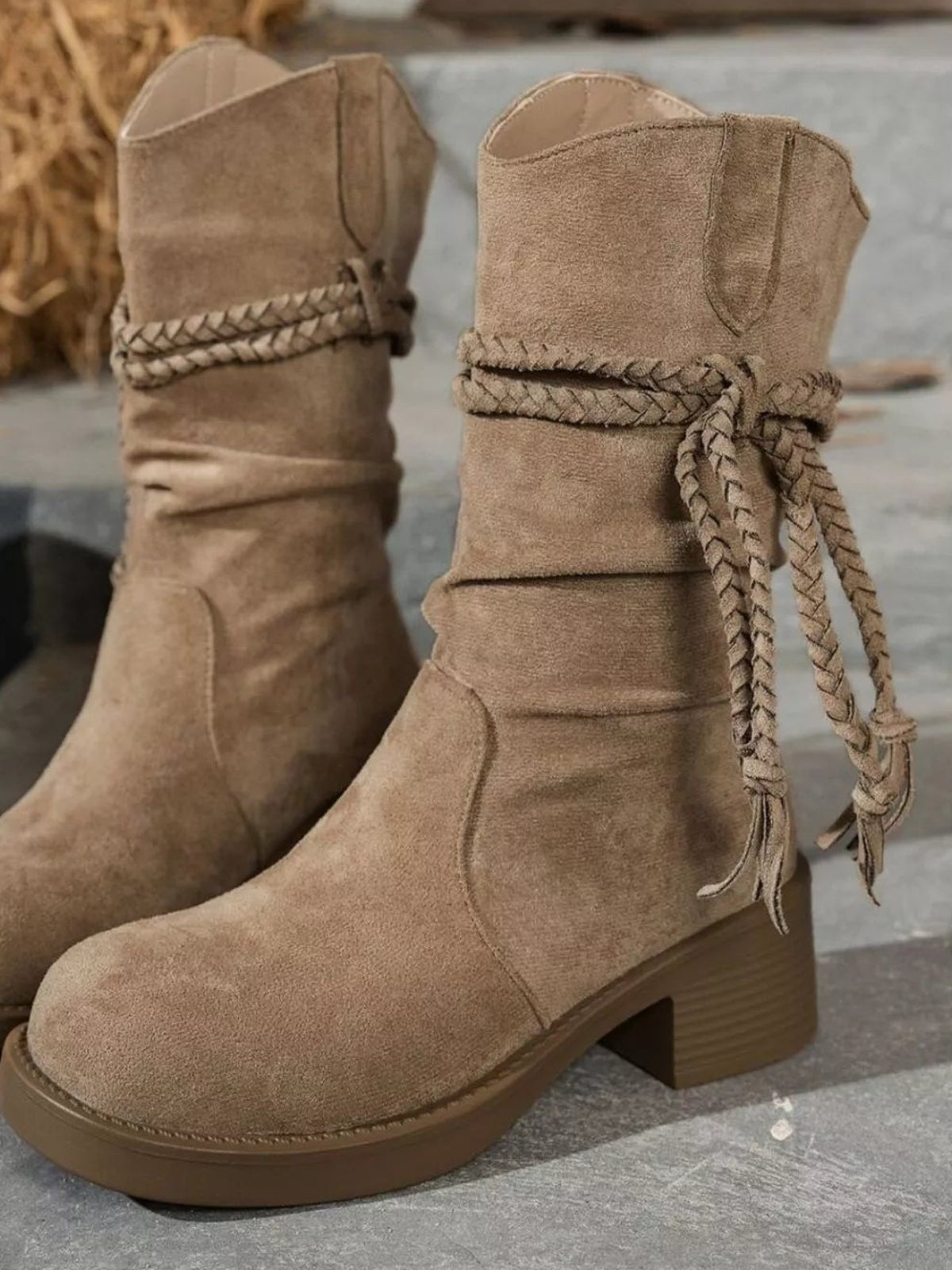 Taupe round-toe block-heel boots with a slouchy mid-calf silhouette, stitched panels, braided ankle ties, and sturdy rubber soles.