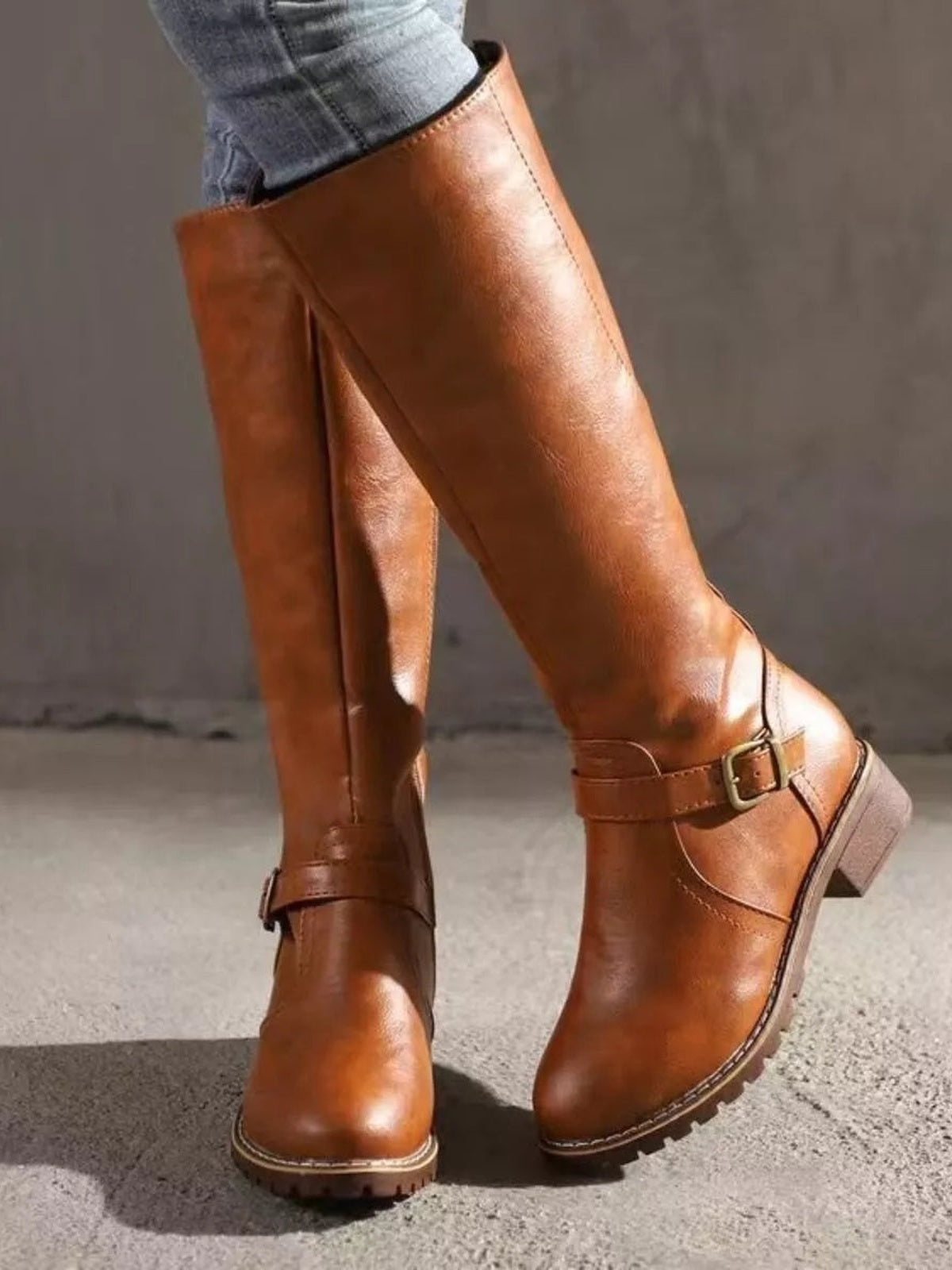 Model wearing brown PU leather round-toe block-heel boots with tall shafts, ankle buckles, stitched soles, and low heels.