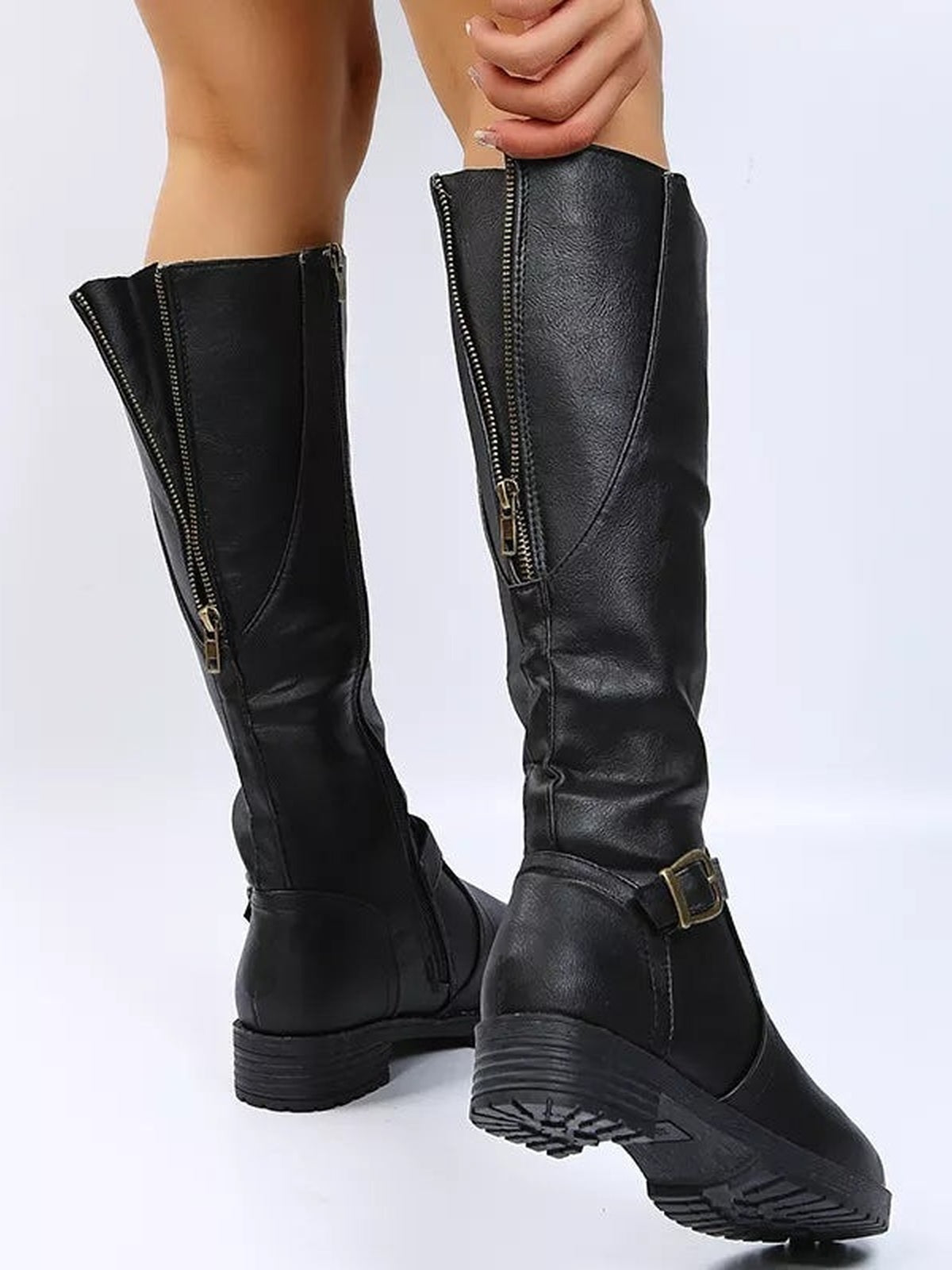 A model displays black PU leather round-toe boots with low block heels, tall shafts, side zippers, and adjustable ankle buckles.