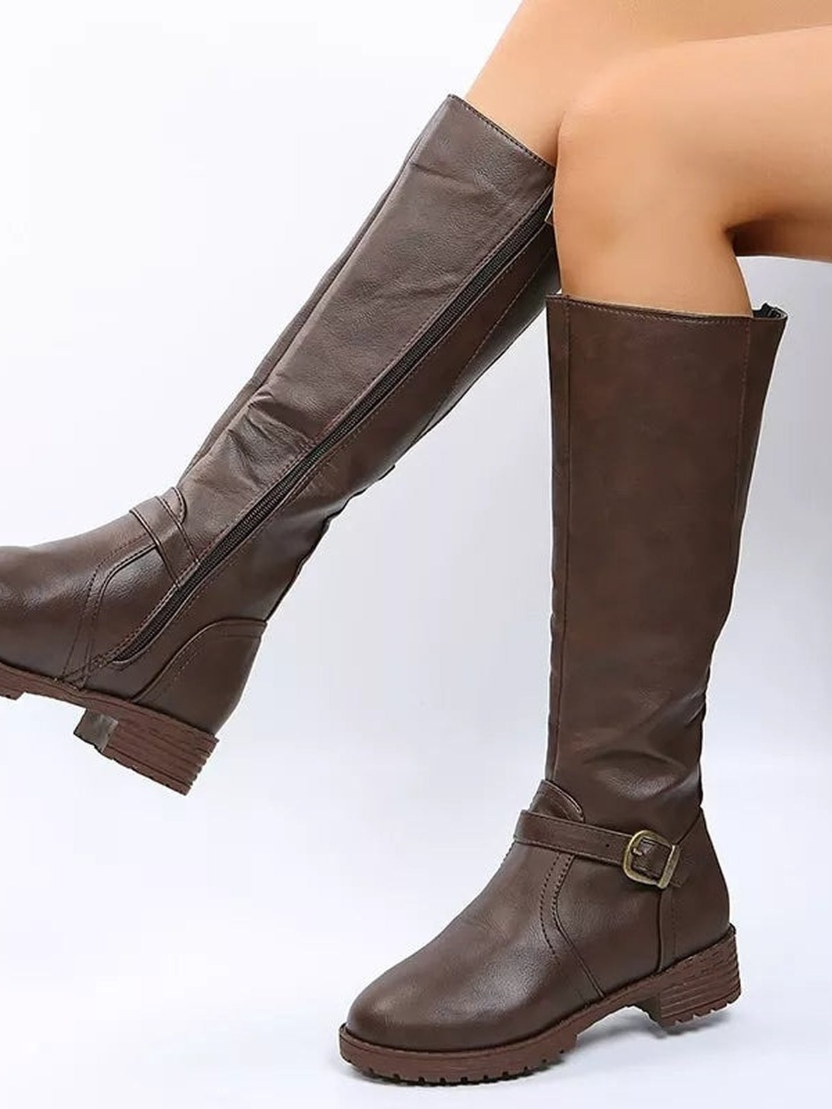 A model wears brown PU leather round-toe block-heel boots with tall shafts, side zippers, buckle straps, and low rubber soles.