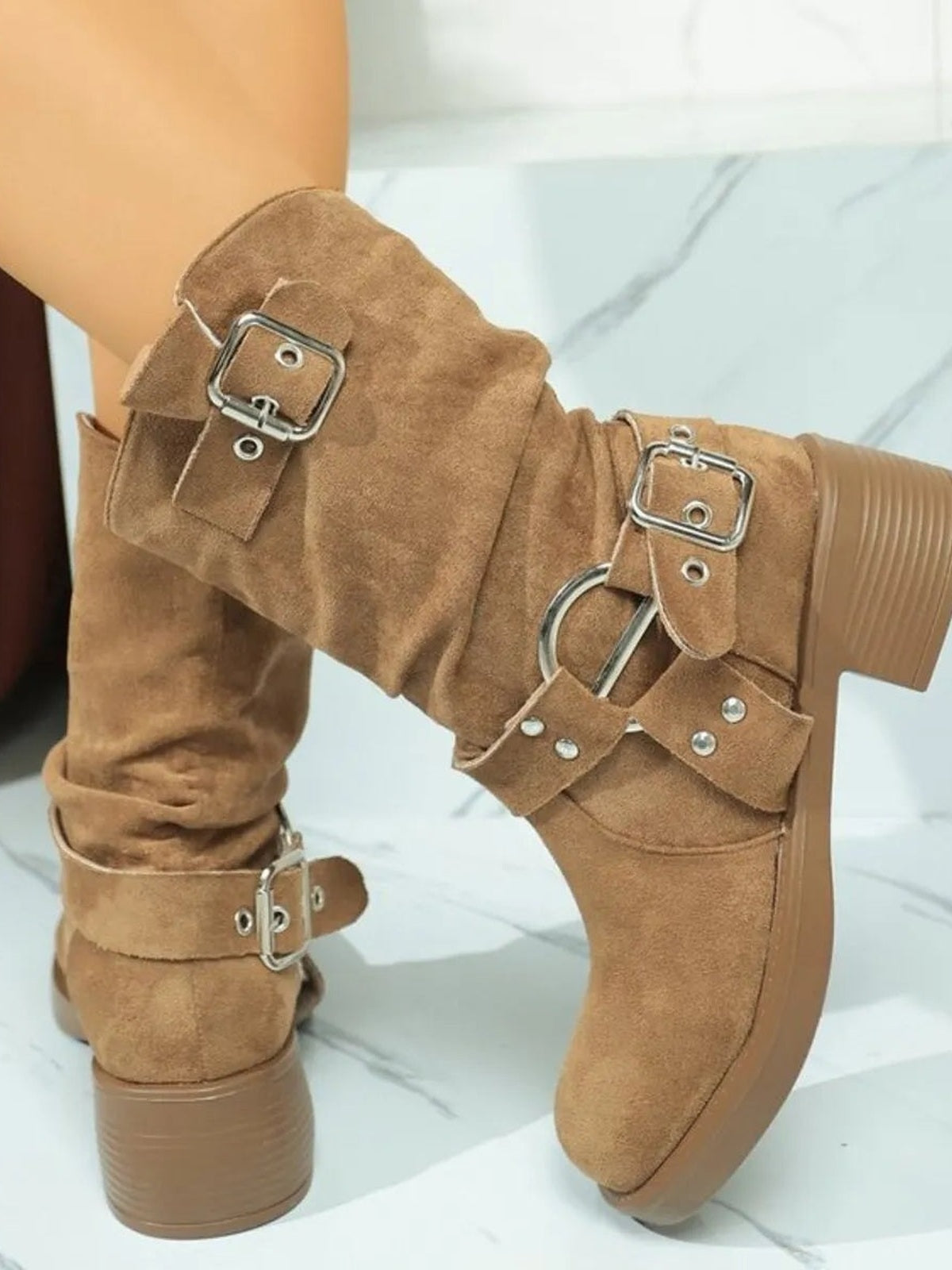 Tan suede round-toe block heel boots feature ruched shafts, multiple adjustable buckle straps, and sturdy low heels for a Western-inspired silhouette.