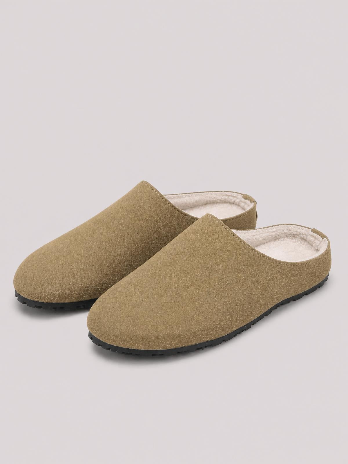 Taupe suede round toe flat slippers feature a slip-on mule silhouette, soft cream lining, and sturdy black rubber soles.