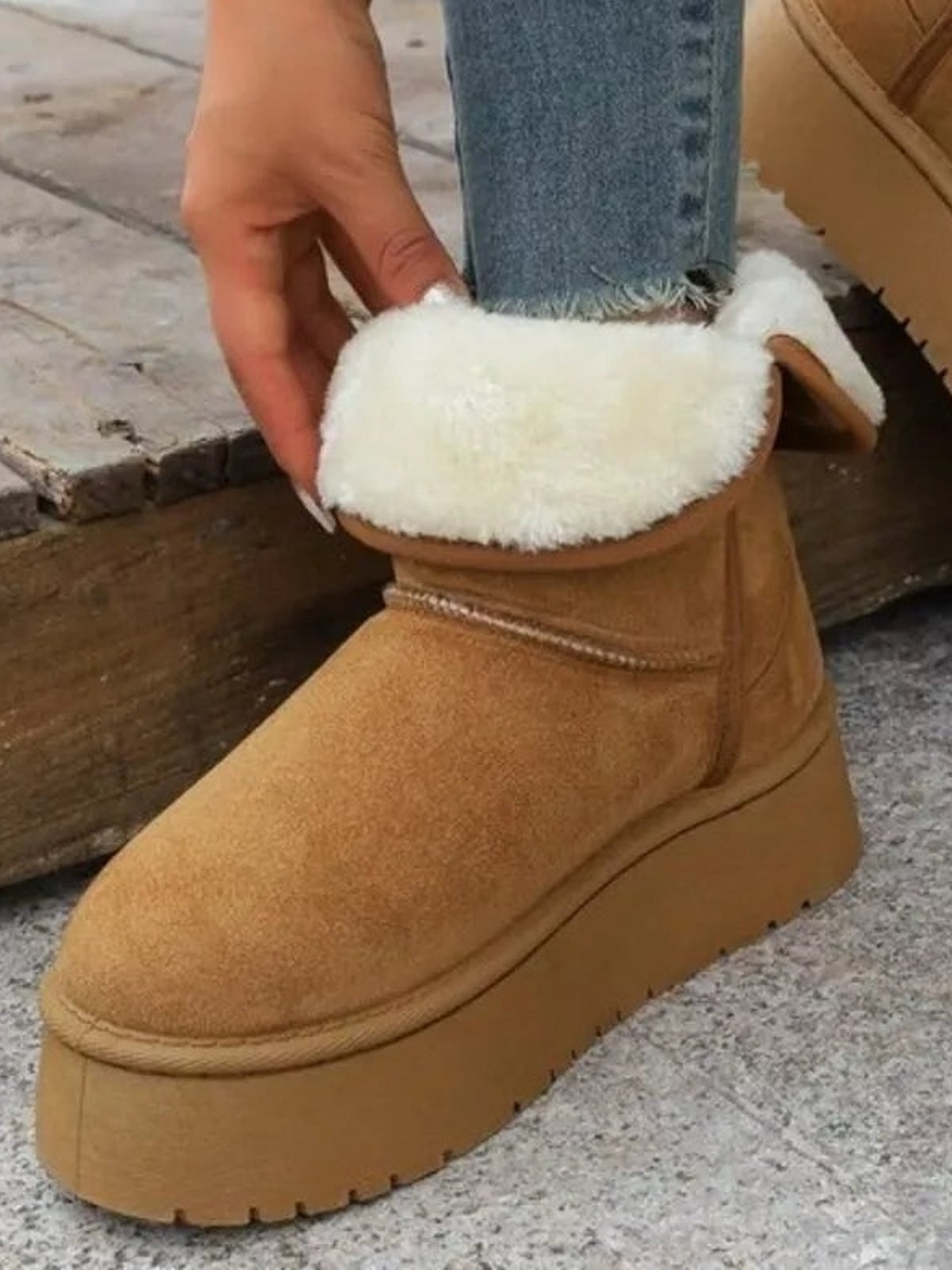 Close-up of a tan round-toe platform boot with plush white lining, textured upper, stitched construction, and a thick lug rubber sole.