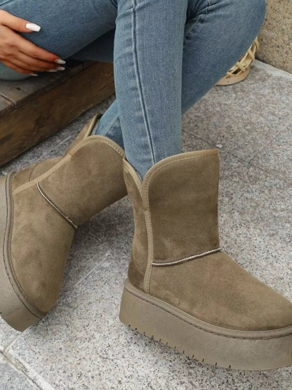 A model sits wearing tan round toe platform boots with soft suede-like uppers, ankle-height construction, stitched trim, and thick flat rubber soles.