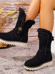 A model wears black round toe platform boots with plush fur cuffs, stitched panels, side buckles, and thick flat rubber lug soles.