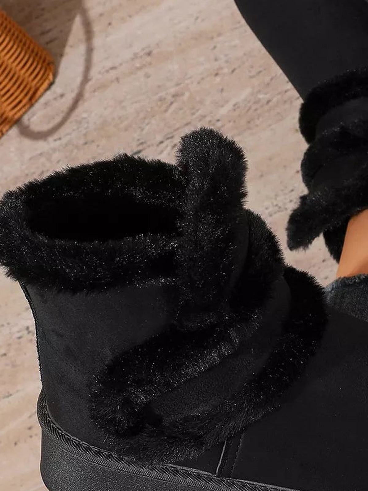 Black round toe platform boot with a plush fluff lining, soft suede upper, and thick rubber sole, shown close up on a model’s foot.