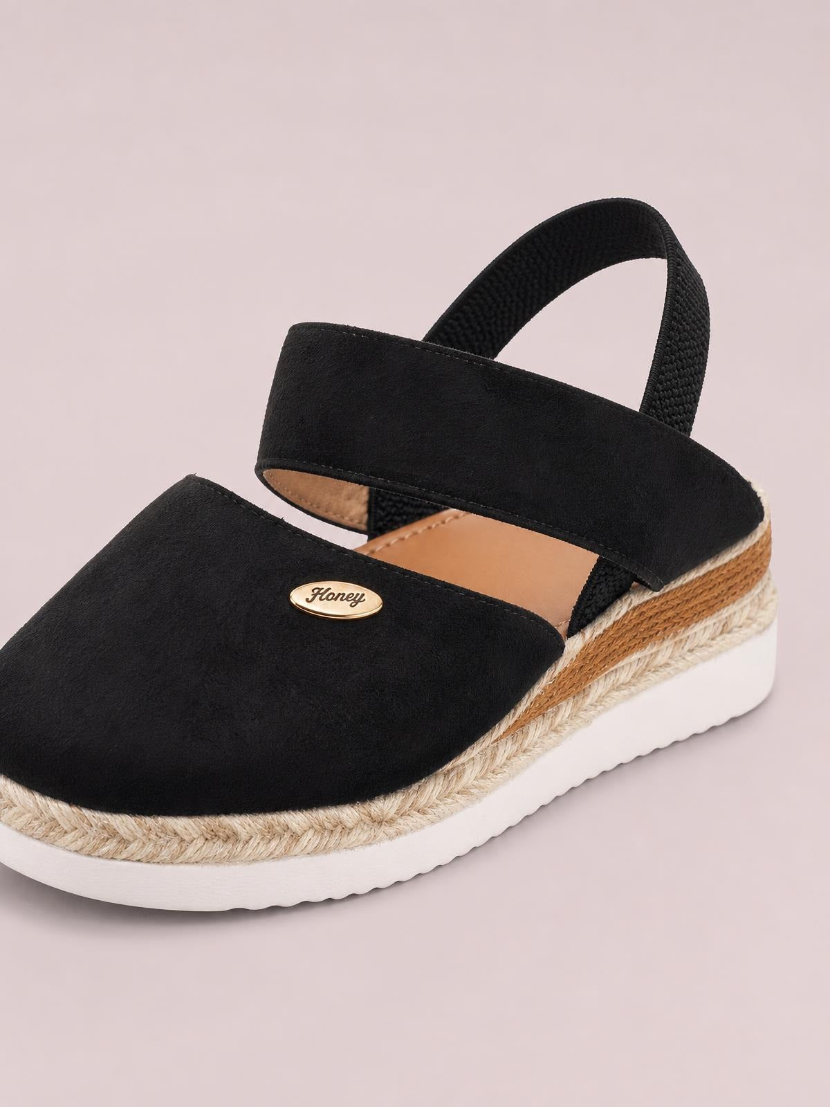 Black round-toe wedge sandals feature a wide canvas toe strap, adjustable slingback strap, braided espadrille midsole, and white rubber platform sole.