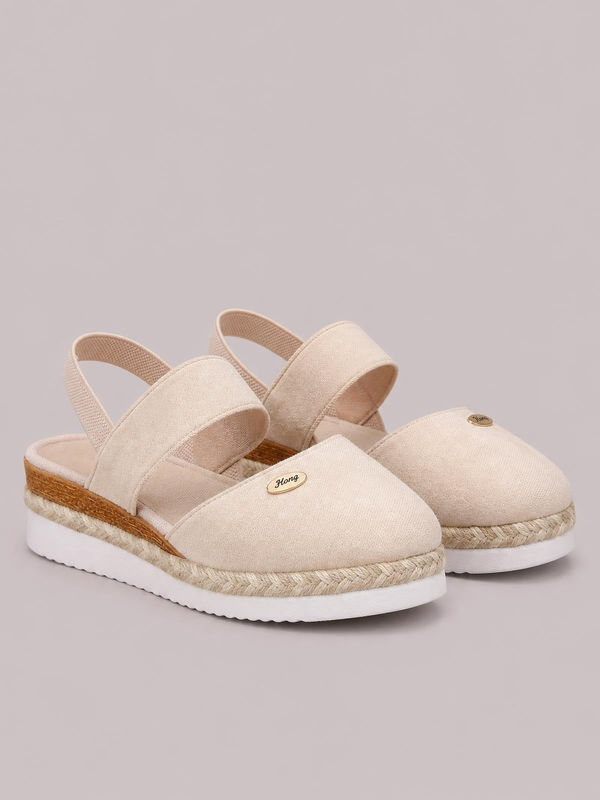 Beige canvas round-toe wedge sandals feature wide straps, slingback heels, braided espadrille-style midsoles, and white rubber outsoles.