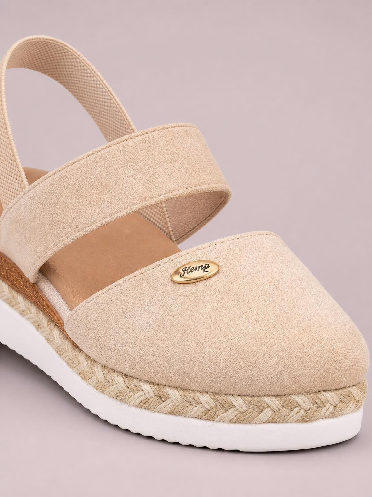 Beige round-toe wedge sandals feature a wide textured upper, adjustable slingback strap, braided espadrille platform, and white rubber sole.