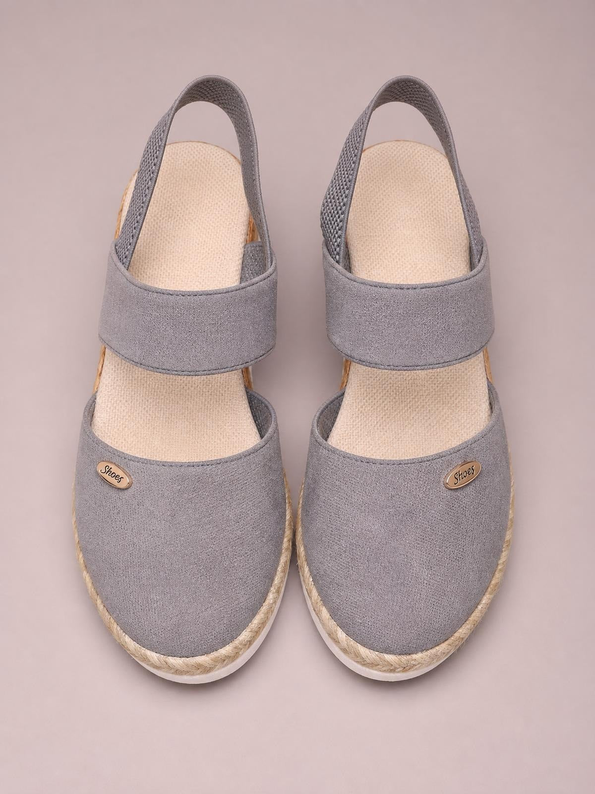 Gray canvas round toe wedge sandals with broad overlapping straps, textured footbeds, rope-trimmed mid-height wedges, and white rubber soles.