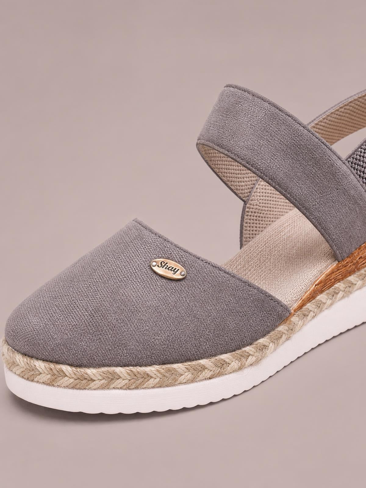 Gray canvas round-toe wedge sandals feature broad straps, a braided espadrille-style midsole, and white rubber platform soles.