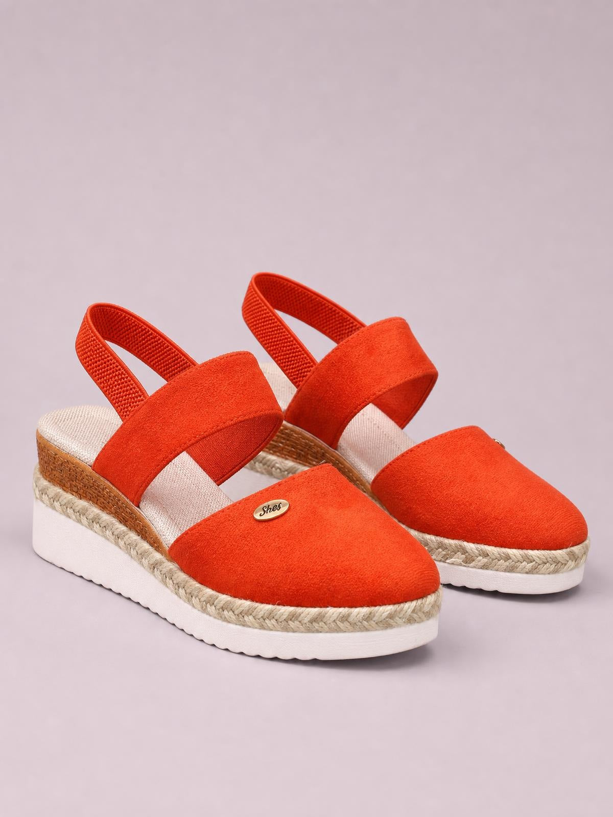 Bright orange round-toe wedge sandals feature wide canvas straps, slingback bands, braided rope trim, and sturdy white rubber midsoles.
