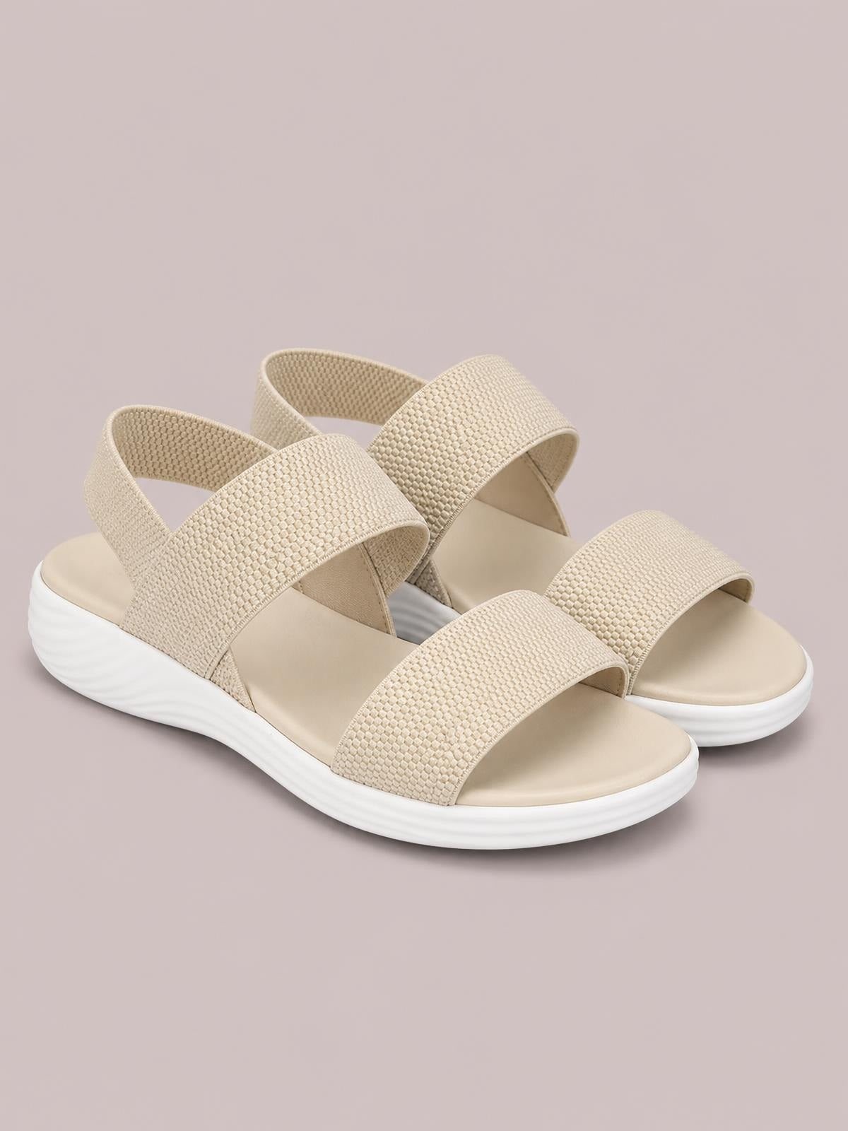 Beige open-toe low-heel sandals with wide textured crossover straps, cushioned footbeds, and a white ridged platform sole.