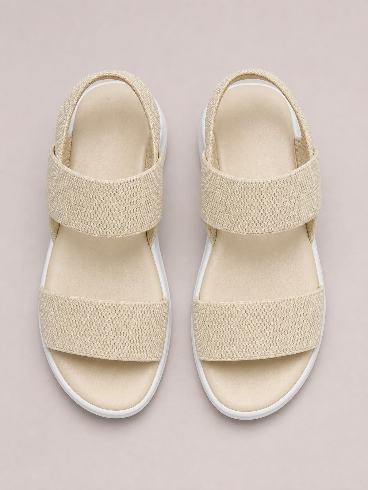 Pair of beige rubber open toe low heel sandals with two wide textured straps, cushioned footbeds, and rounded soles.