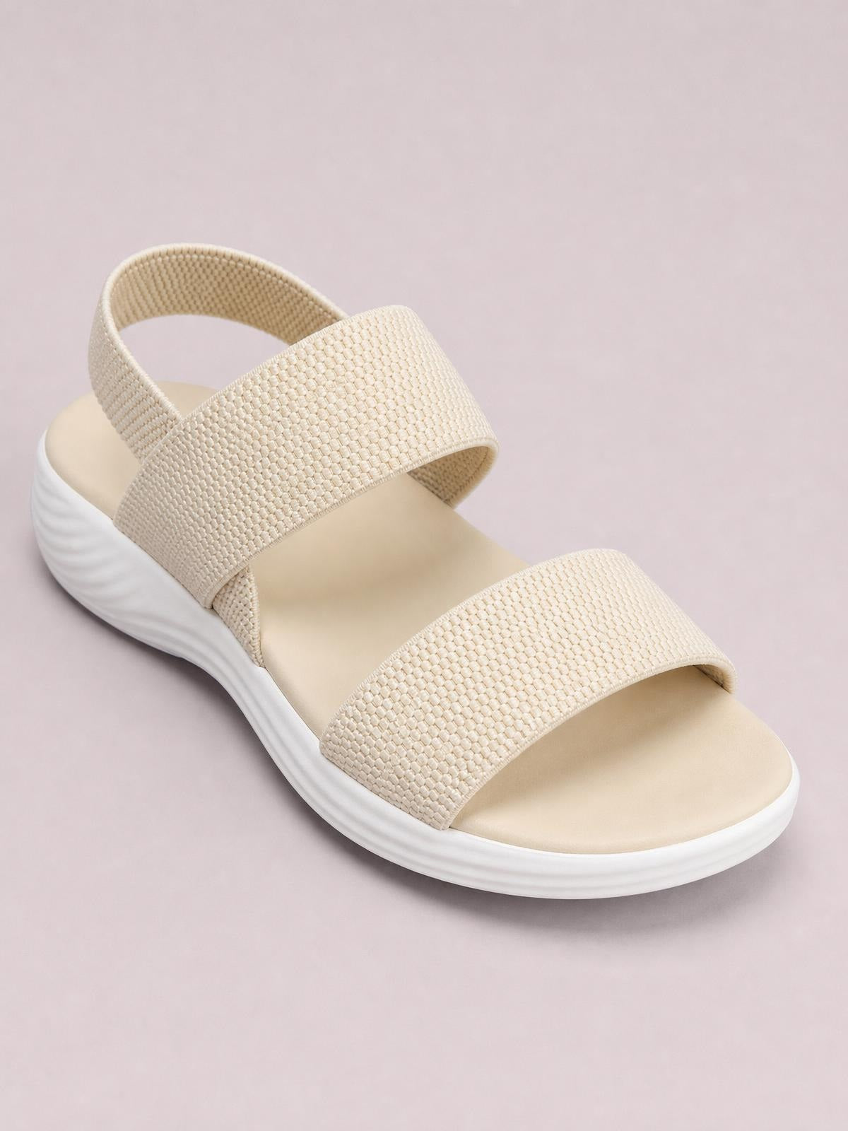 Beige open toe low heel sandals feature wide textured straps, an adjustable-looking slingback band, and a softly contoured rubber sole with a low wedge silhouette.