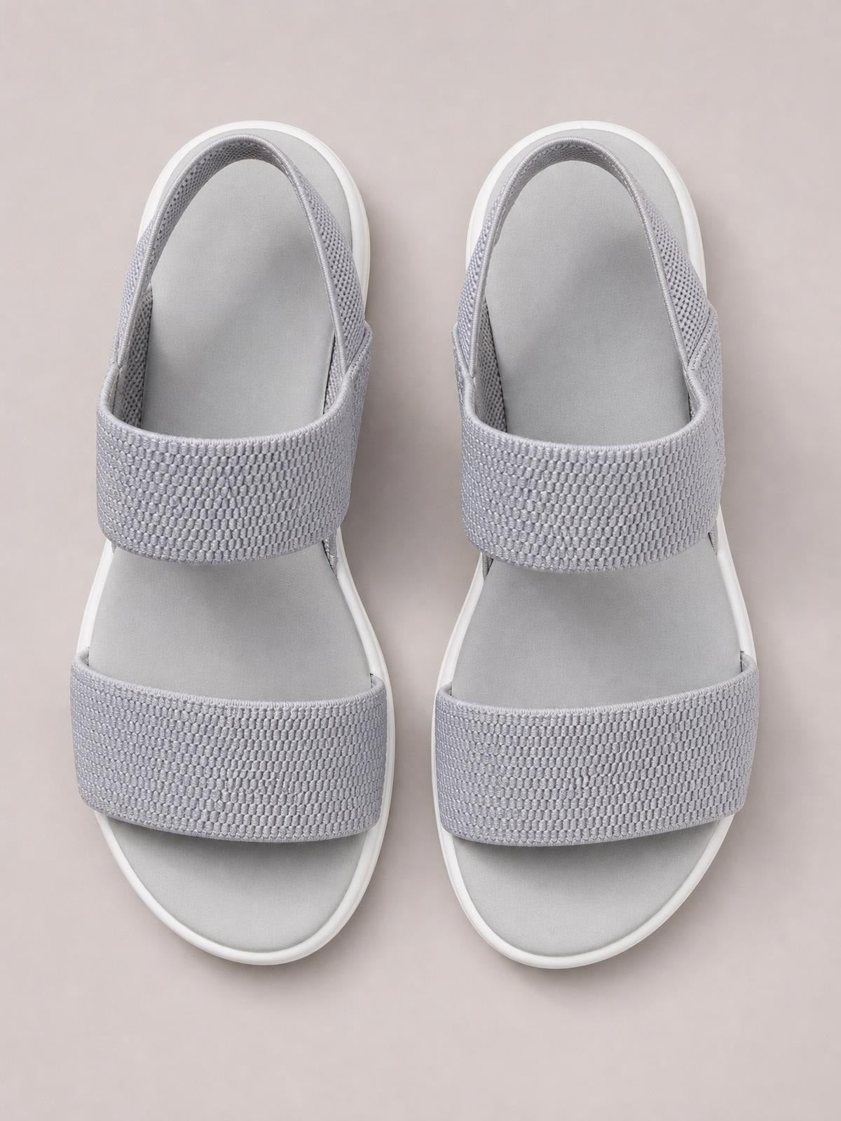 Pair of light gray rubber open-toe sandals with low heels, wide textured crossover straps, cushioned footbeds, and rounded soles.