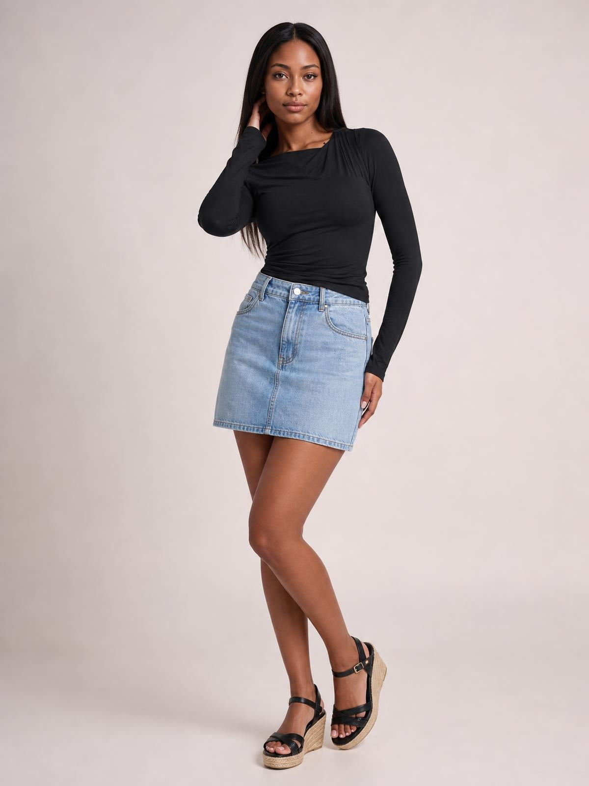 Model poses in a fitted black ruched asymmetrical-neck long-sleeve T-shirt with a sleek, stretch silhouette.