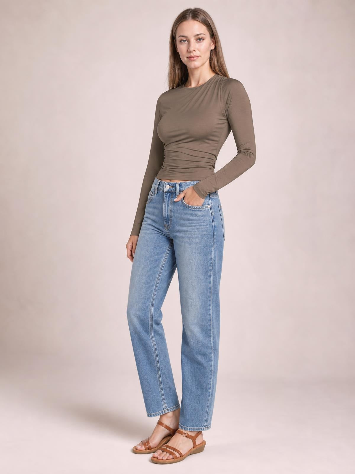 Model wears a taupe ruched asymmetrical-neck long-sleeve T-shirt with a fitted silhouette and gathered construction through the waist.