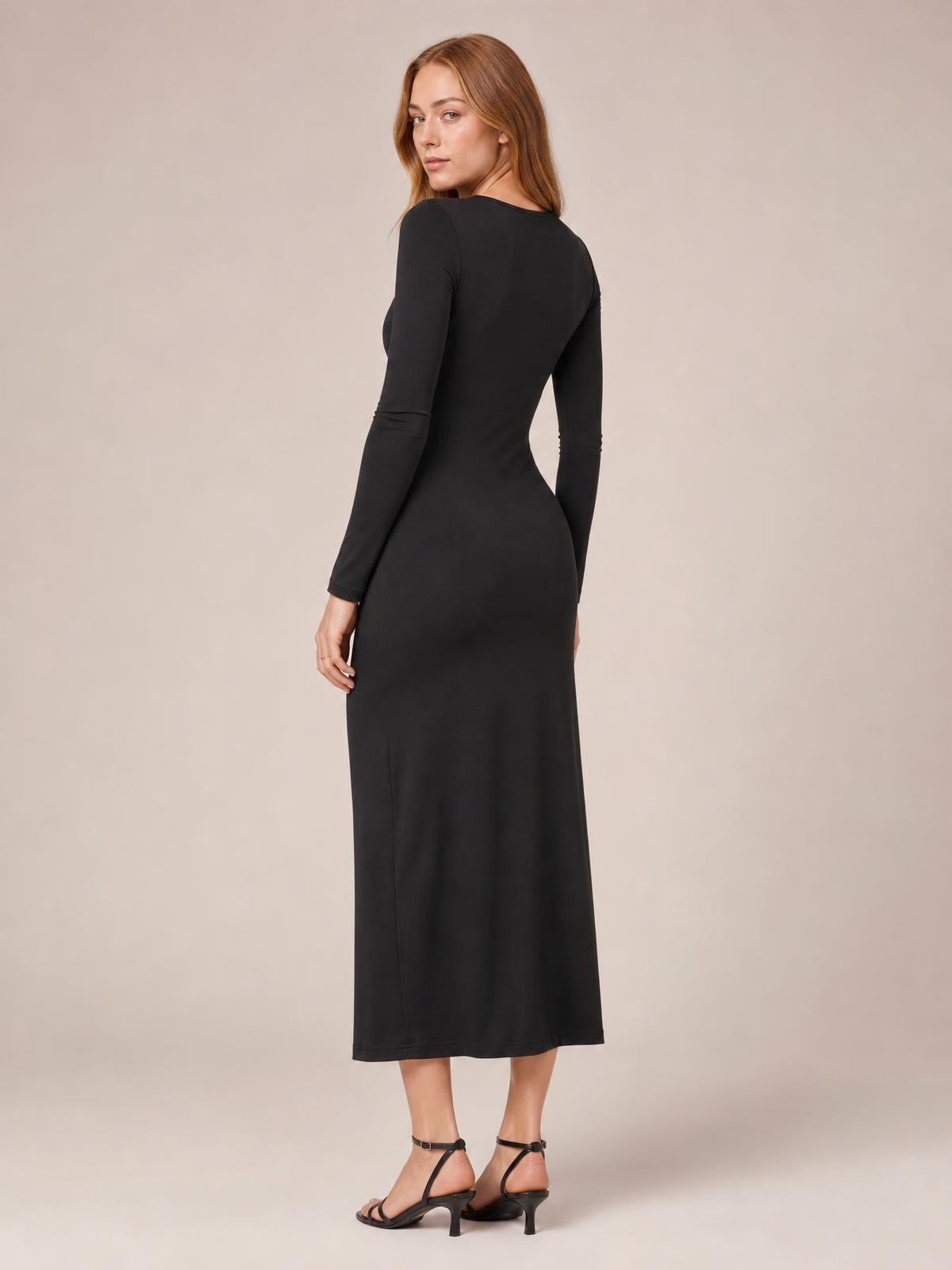 A model looks over her shoulder in a black long-sleeve bodycon dress with a fitted silhouette and straight midi-length skirt.