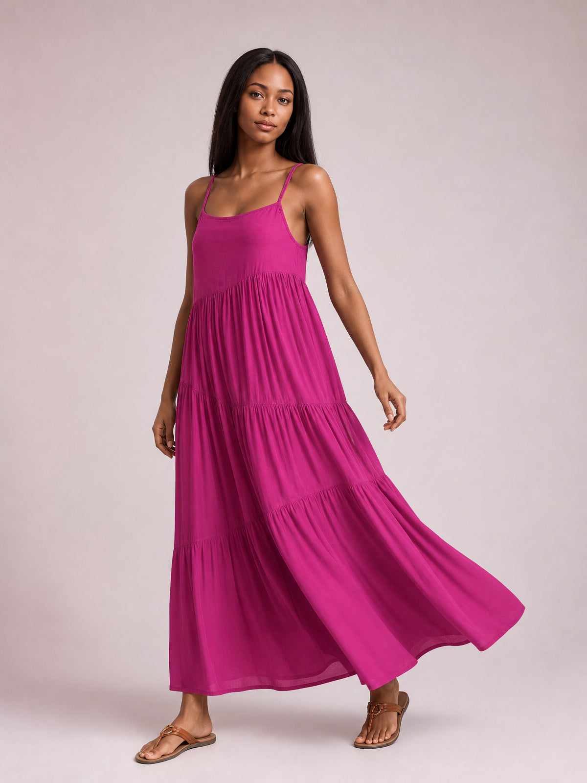 Model wears a magenta ruched tiered spaghetti strap maxi dress with a scoop neckline, flowing full skirt, and swaying floor-skimming silhouette.
