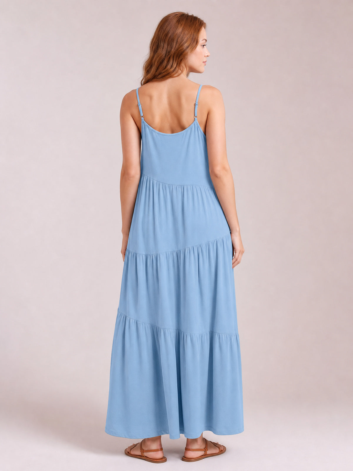 Model shown from the back in a light blue ruched tiered spaghetti strap maxi dress with a flowing, floor-length silhouette and adjustable straps.