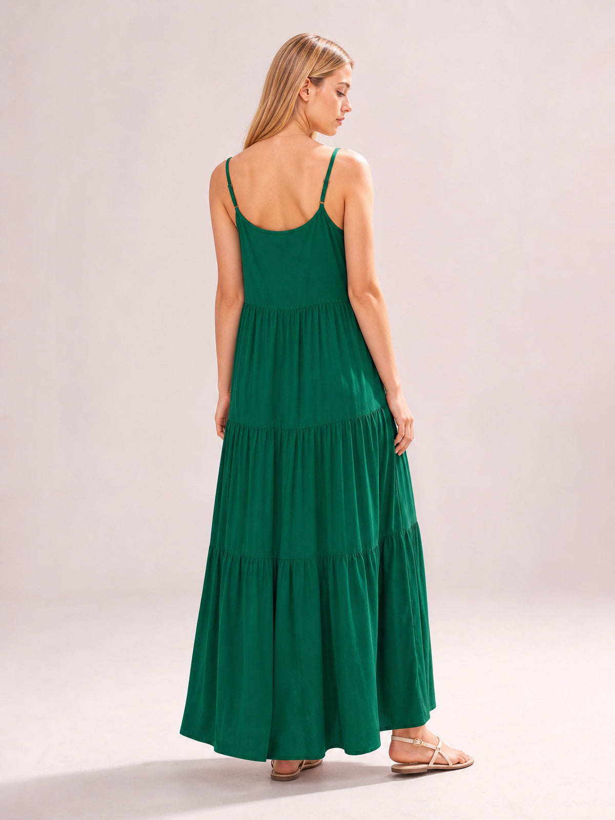 Model shown from the back in a deep green ruched tiered spaghetti strap maxi dress with a scoop back, gathered skirt, and flowing floor-length silhouette.